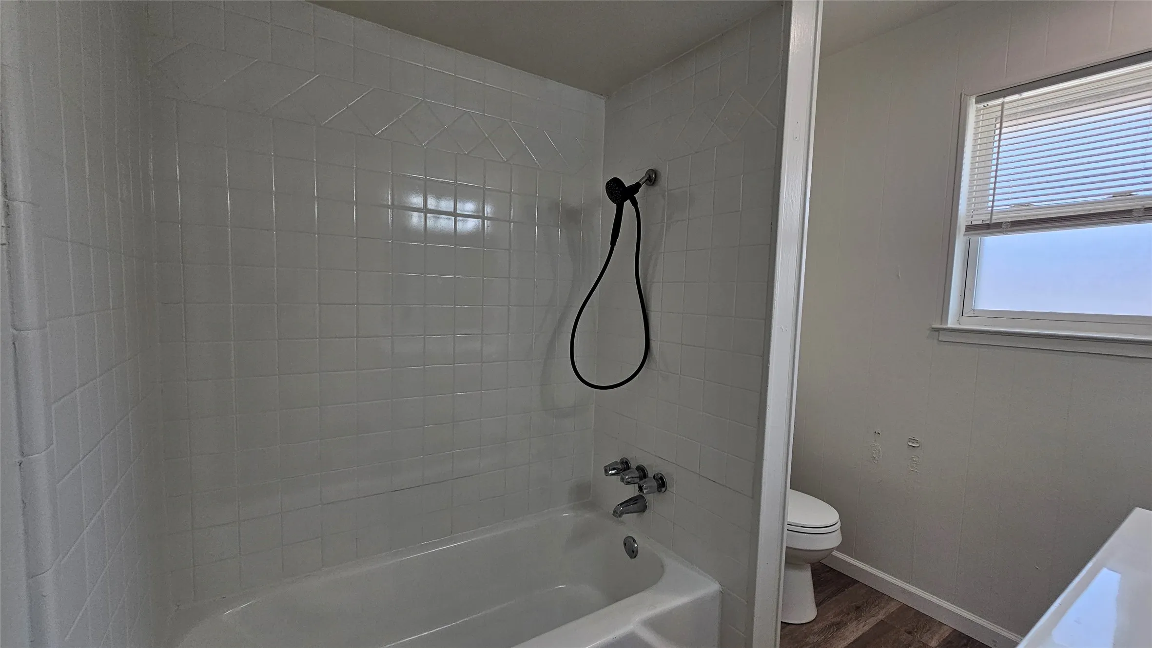 Full bathroom featuring wood finished floors and washtub / shower combination