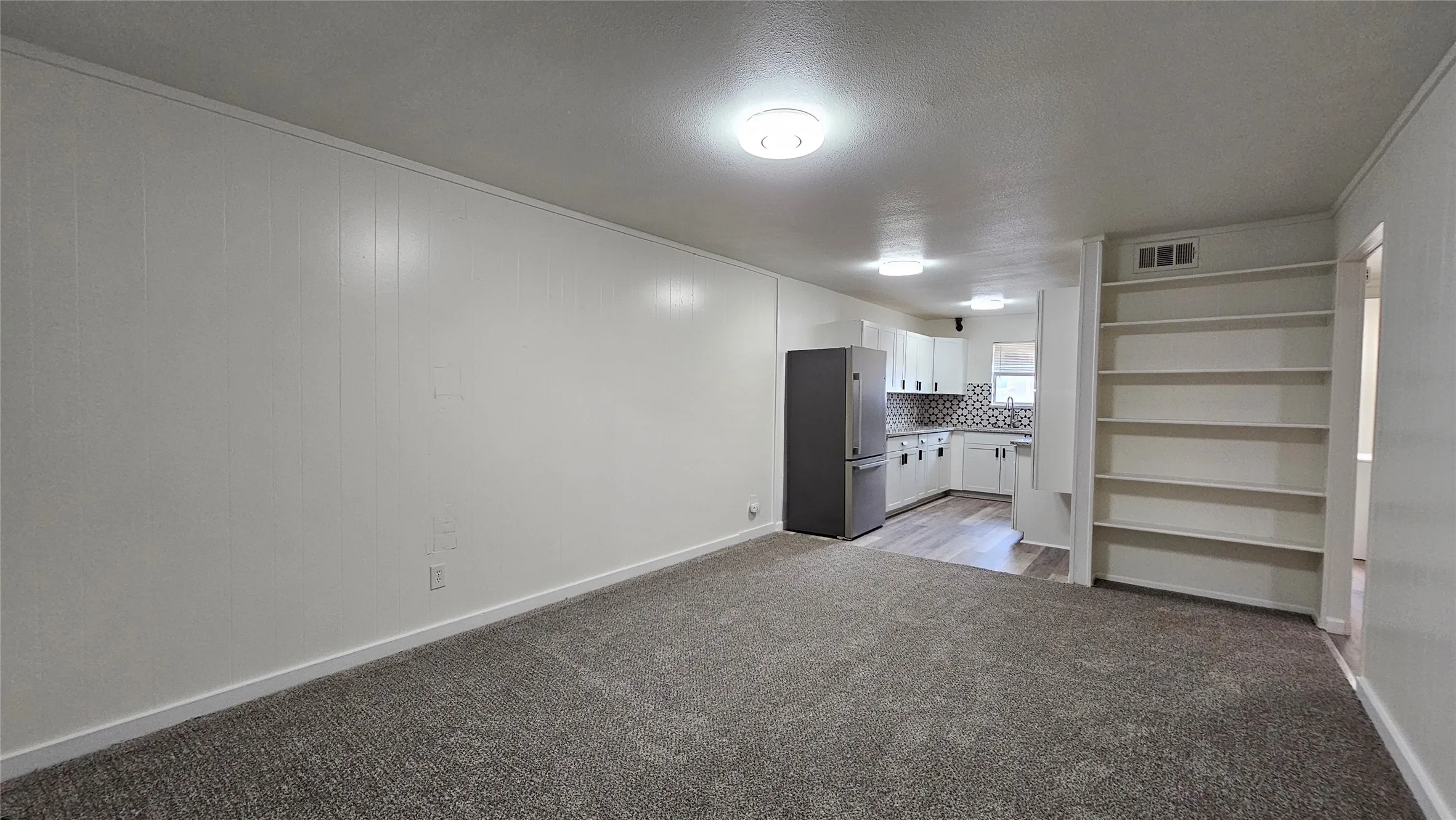 Unfurnished living room featuring carpet and a textured ceiling