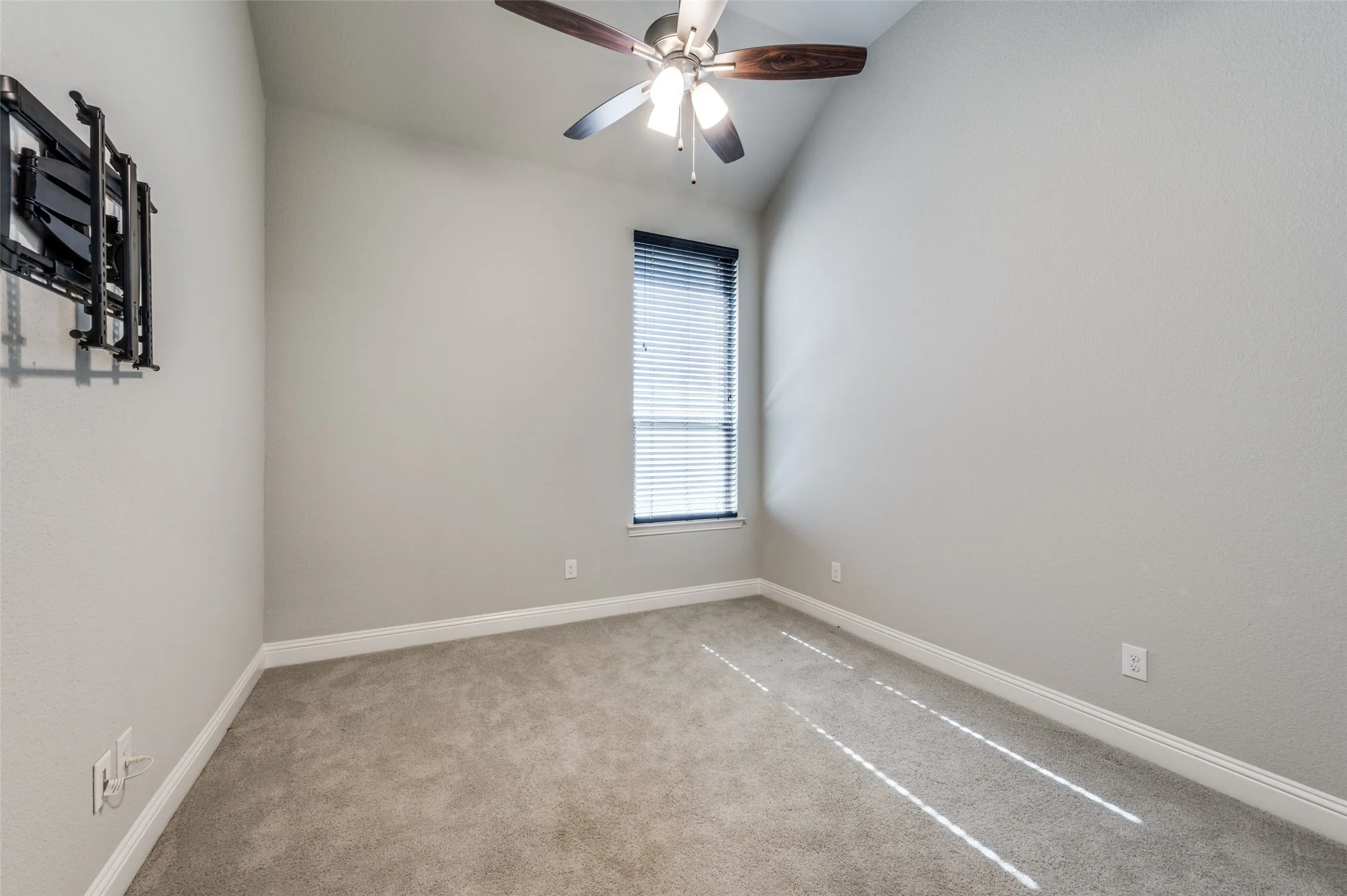 Spare bedroom with carpet floors, ceiling fan, and vaulted ceiling