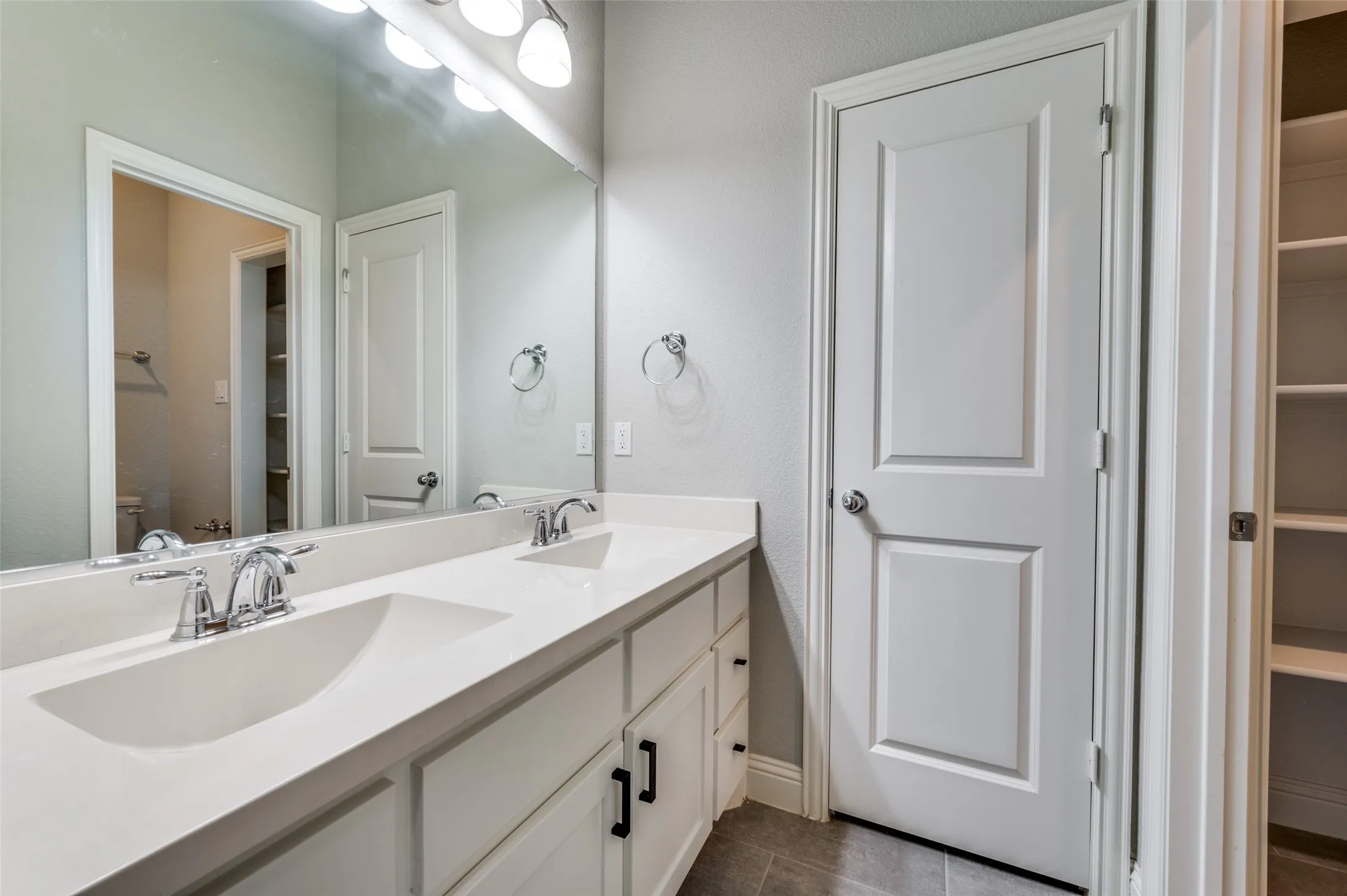 Full bath with double vanity, a spacious closet, and tile patterned flooring
