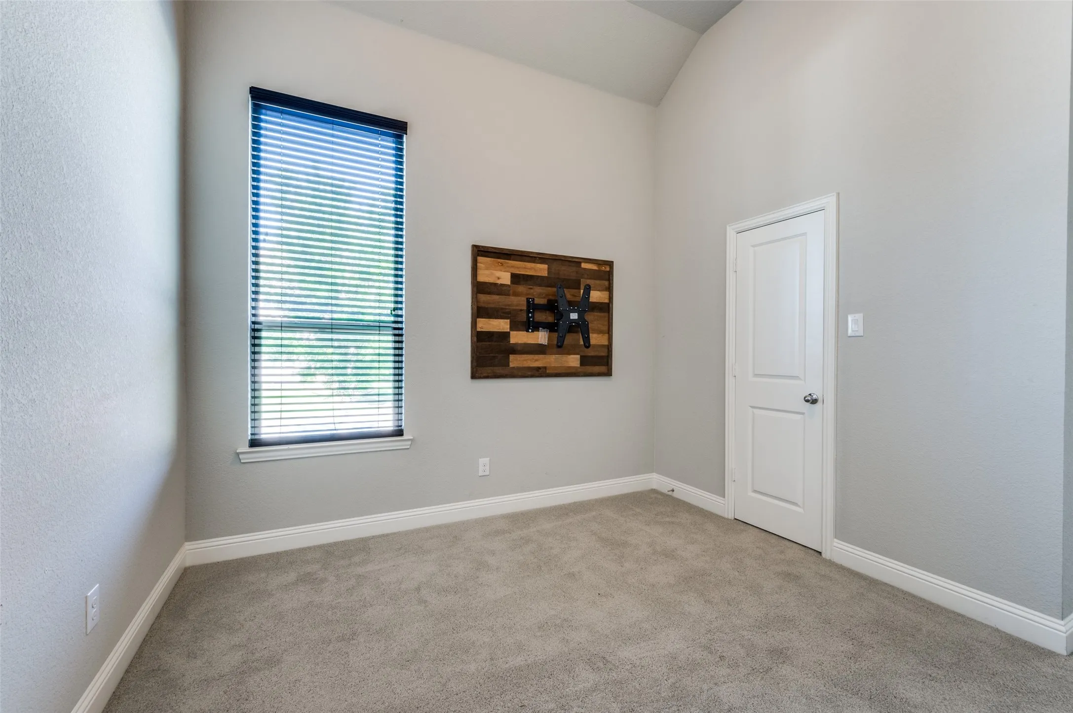 Spare bedroom featuring carpet and lofted ceiling