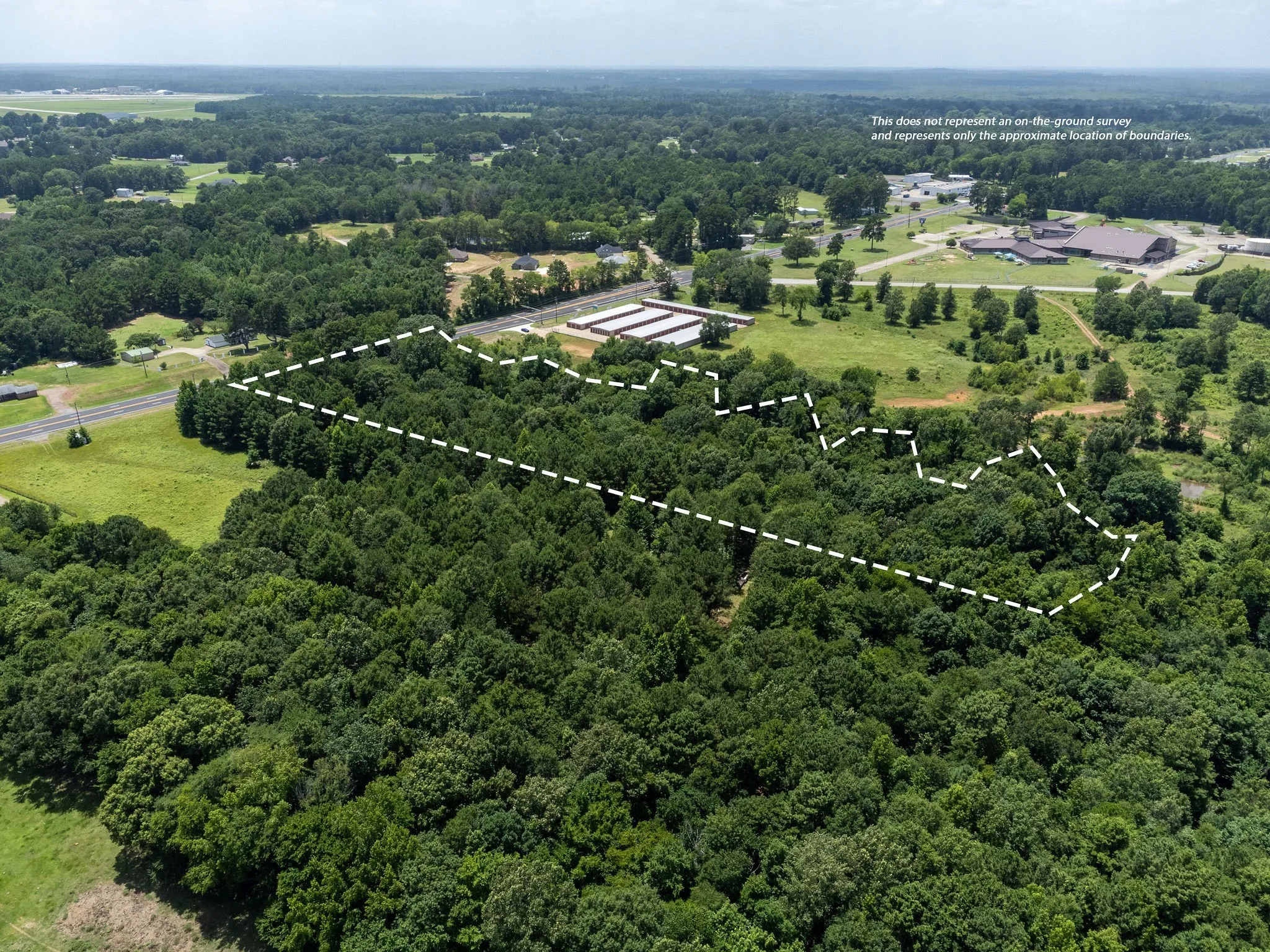 Aerial view of property and surrounding area featuring a forest and property parcel outlined
