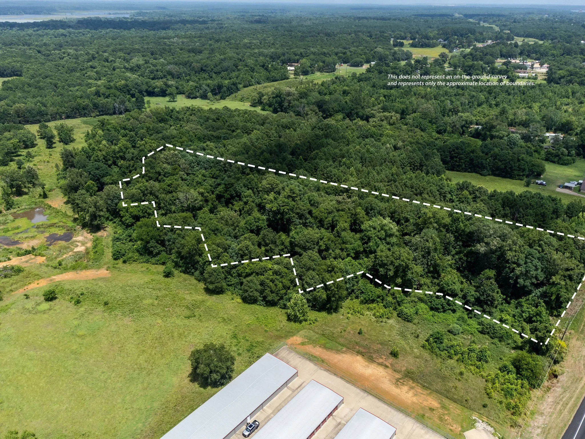 Aerial view of property's location featuring property parcel outlined and a heavily wooded area
