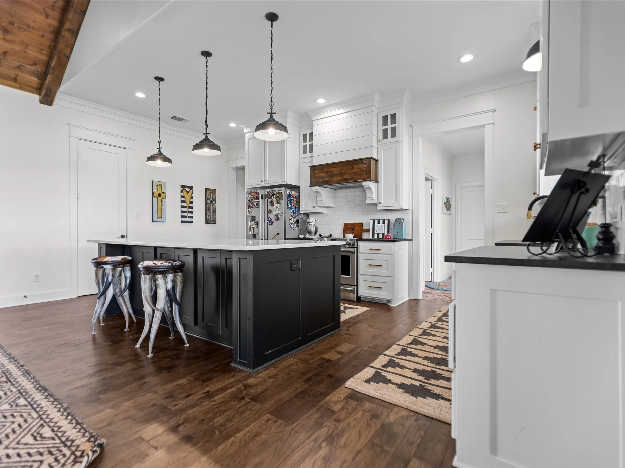 Kitchen featuring premium appliances, white cabinetry, dark wood finished floors, tasteful backsplash, and a kitchen island