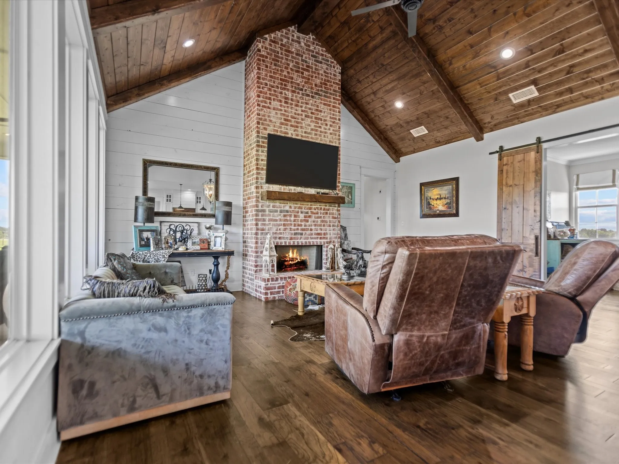Living room with a wood ceiling with exposed beams, a barn door, a fireplace, dark wood-type flooring, and high vaulted ceiling