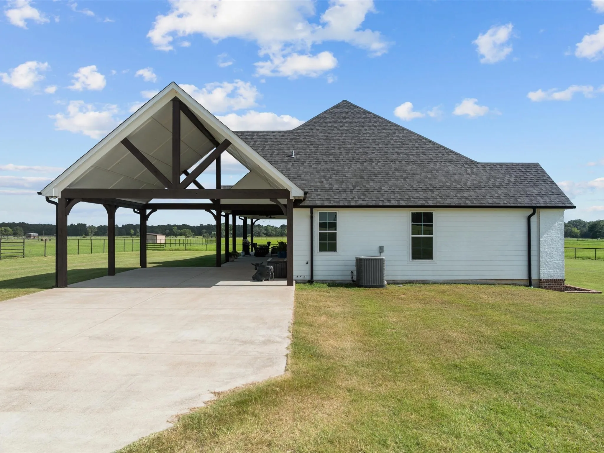 View of side of home with roof with shingles and driveway