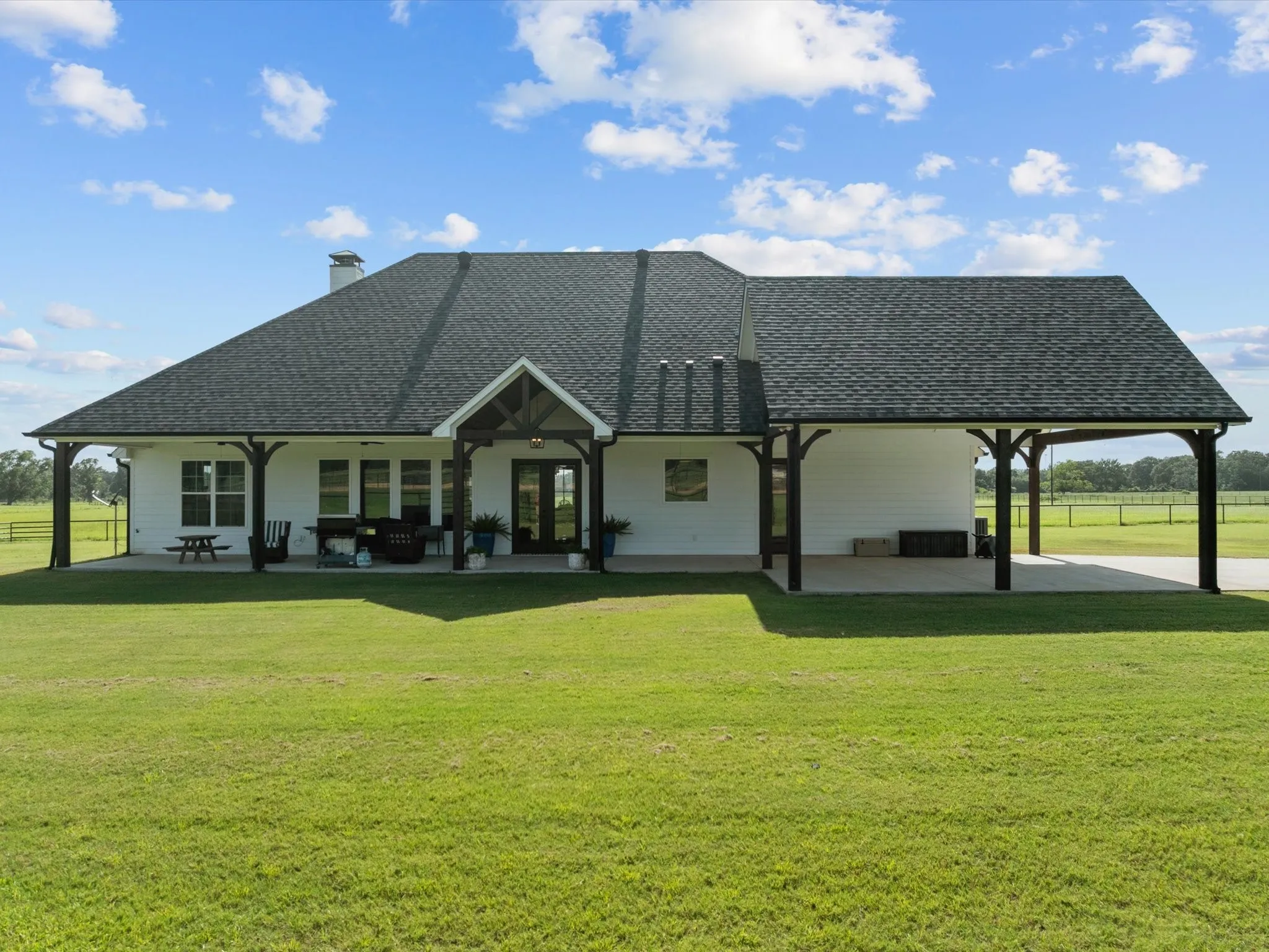 Back of house with a shingled roof, a patio, a chimney, and a yard