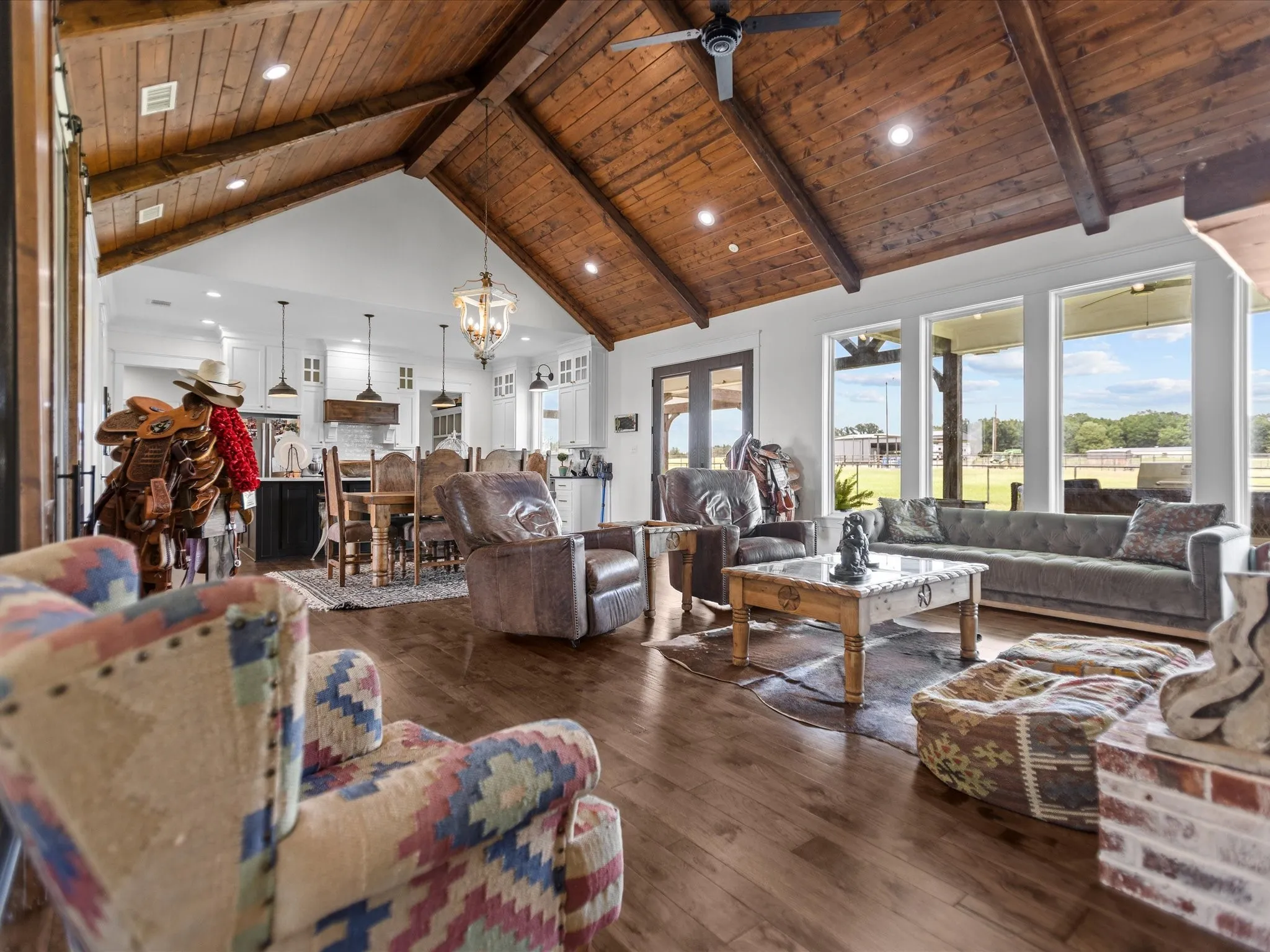 Living area with a wooden ceiling with exposed beams, a ceiling fan, high vaulted ceiling, hardwood / wood-style flooring, and a chandelier