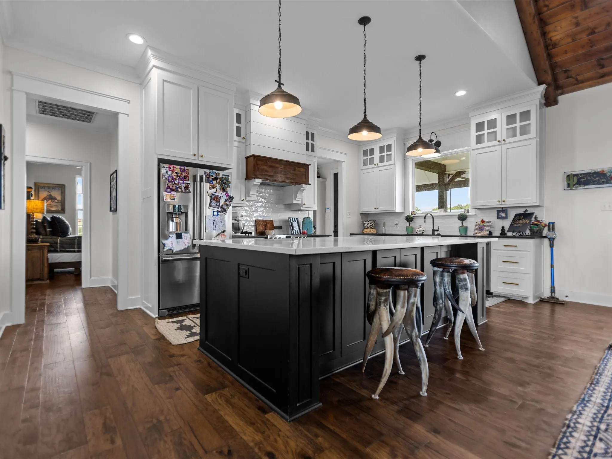 Kitchen with high end refrigerator, a kitchen island, white cabinets, glass insert cabinets, and dark wood-type flooring