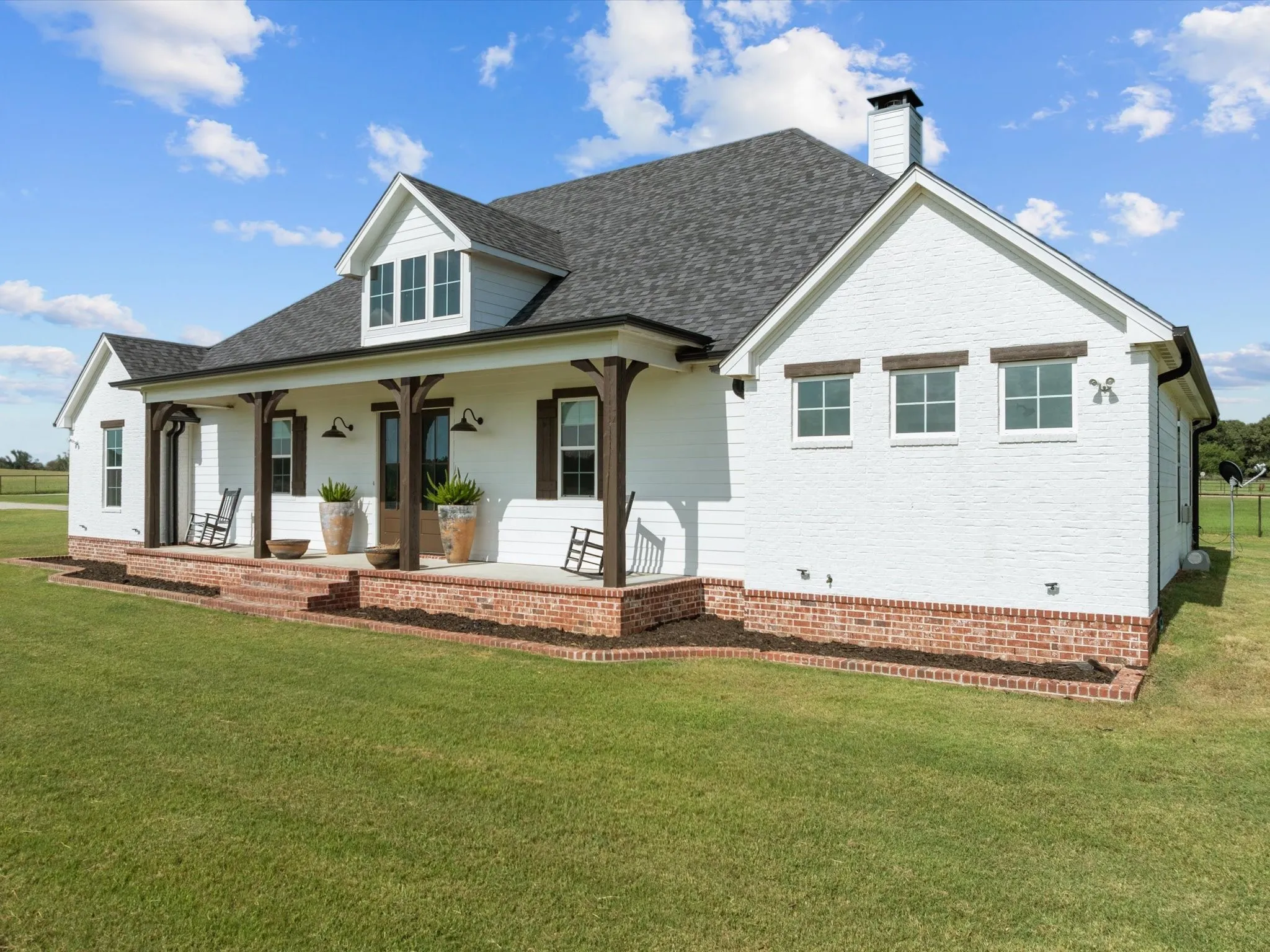 View of front facade with covered porch, a front yard, a chimney, and roof with shingles