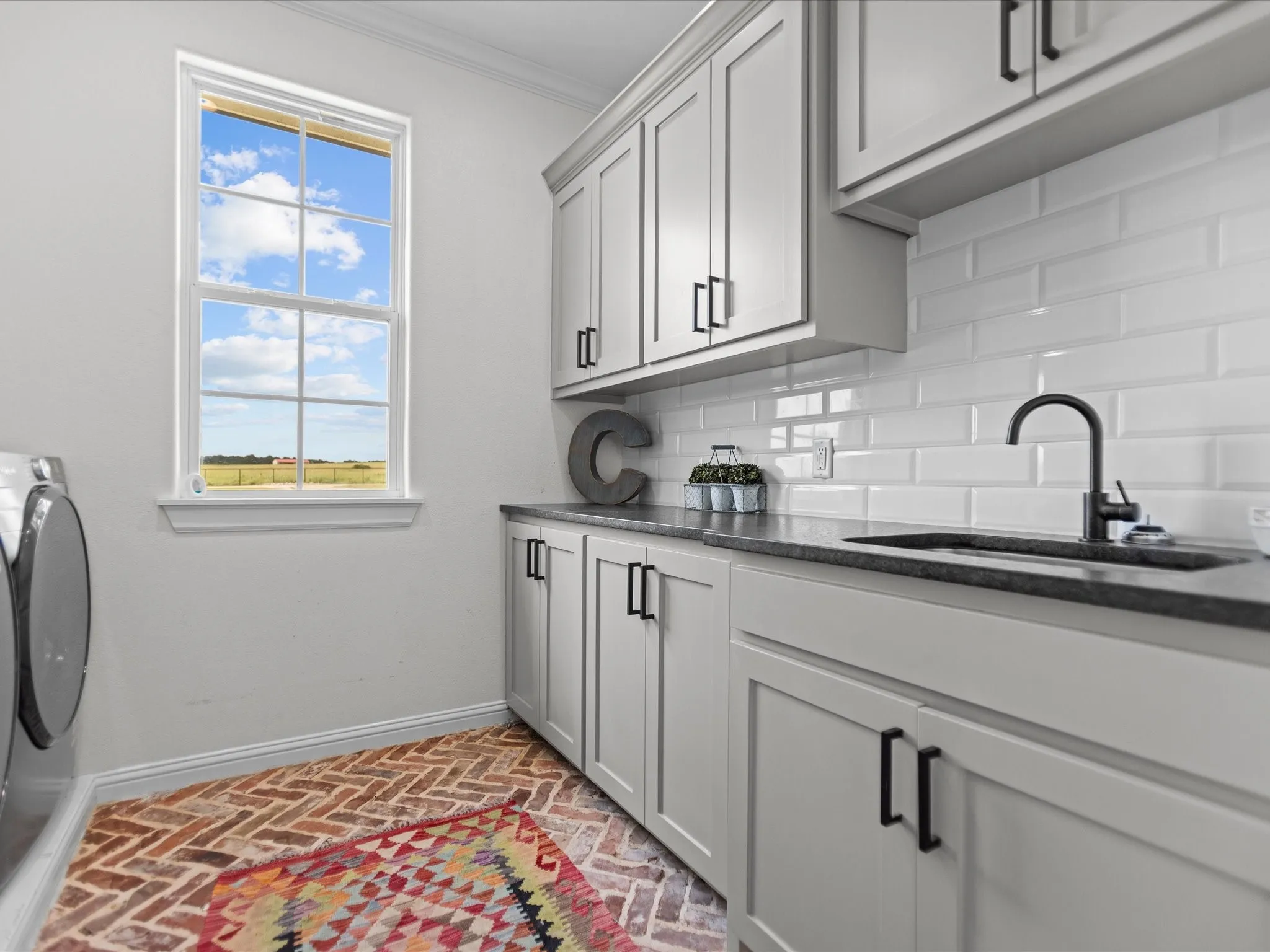 Laundry area with brick flooring, cabinet space, crown molding, healthy amount of natural light, and washer / dryer
