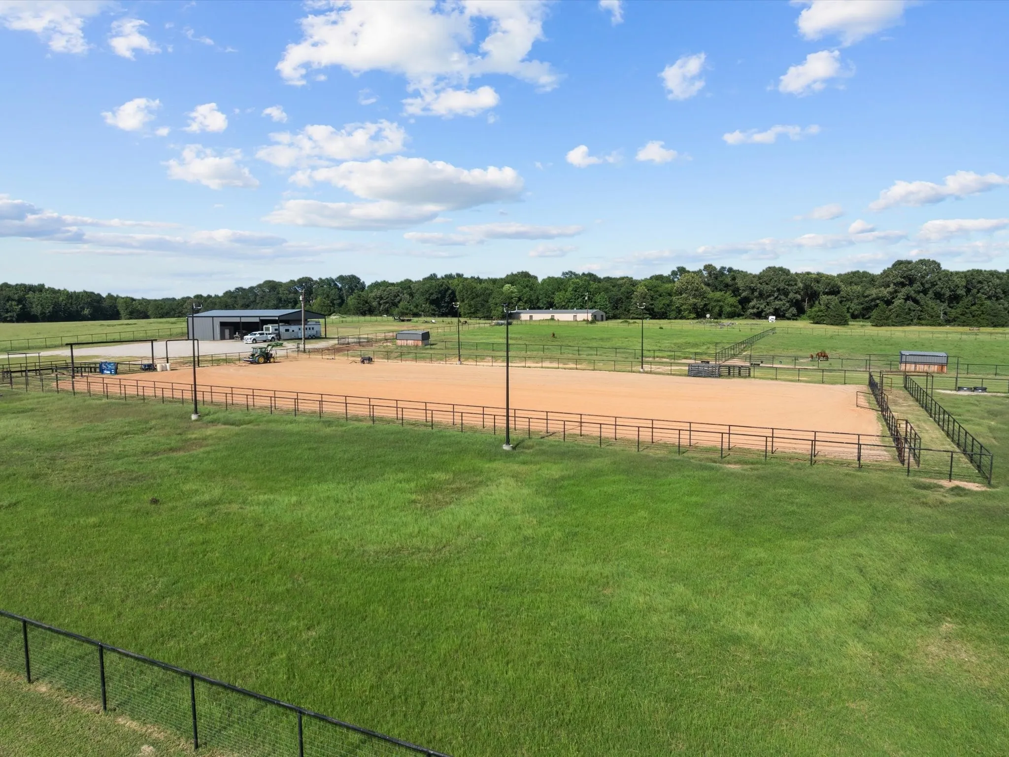View of yard with a rural view, an enclosed riding area, an outbuilding, and a pole building