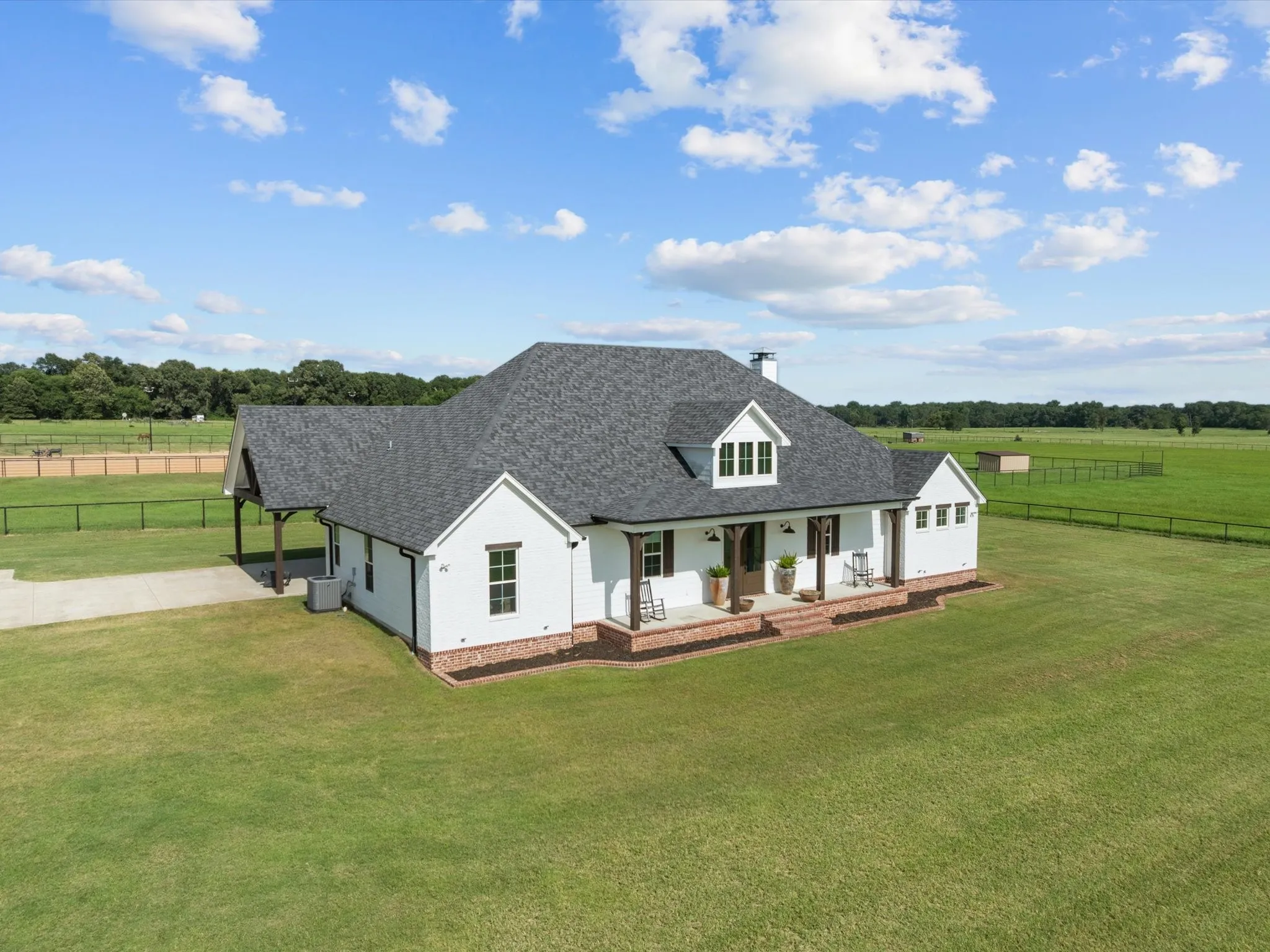 Modern farmhouse with covered porch, a shingled roof, a view of countryside, and concrete driveway