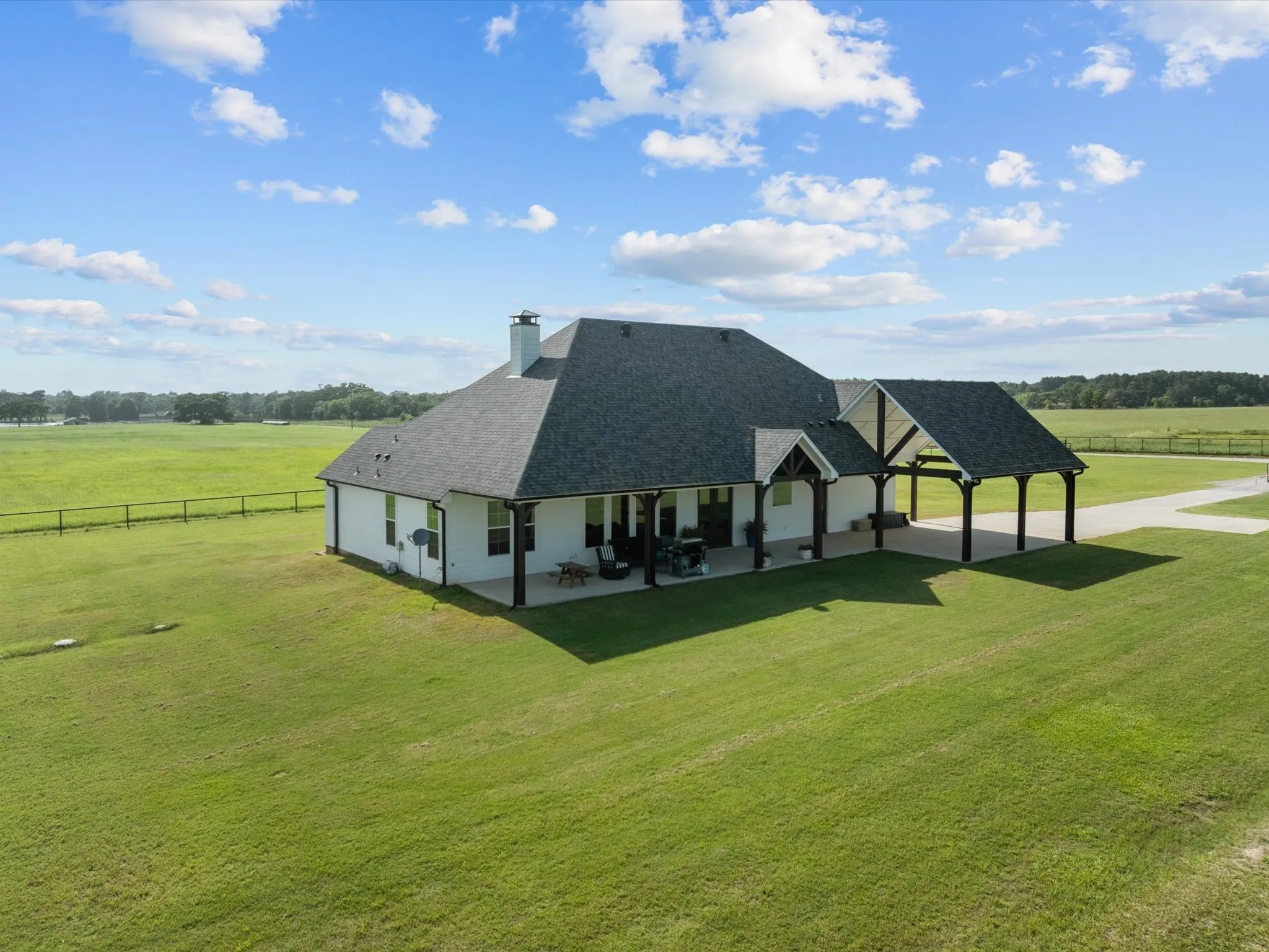 Back of house featuring roof with shingles, a chimney, a view of rural / pastoral area, a patio area, and a gazebo