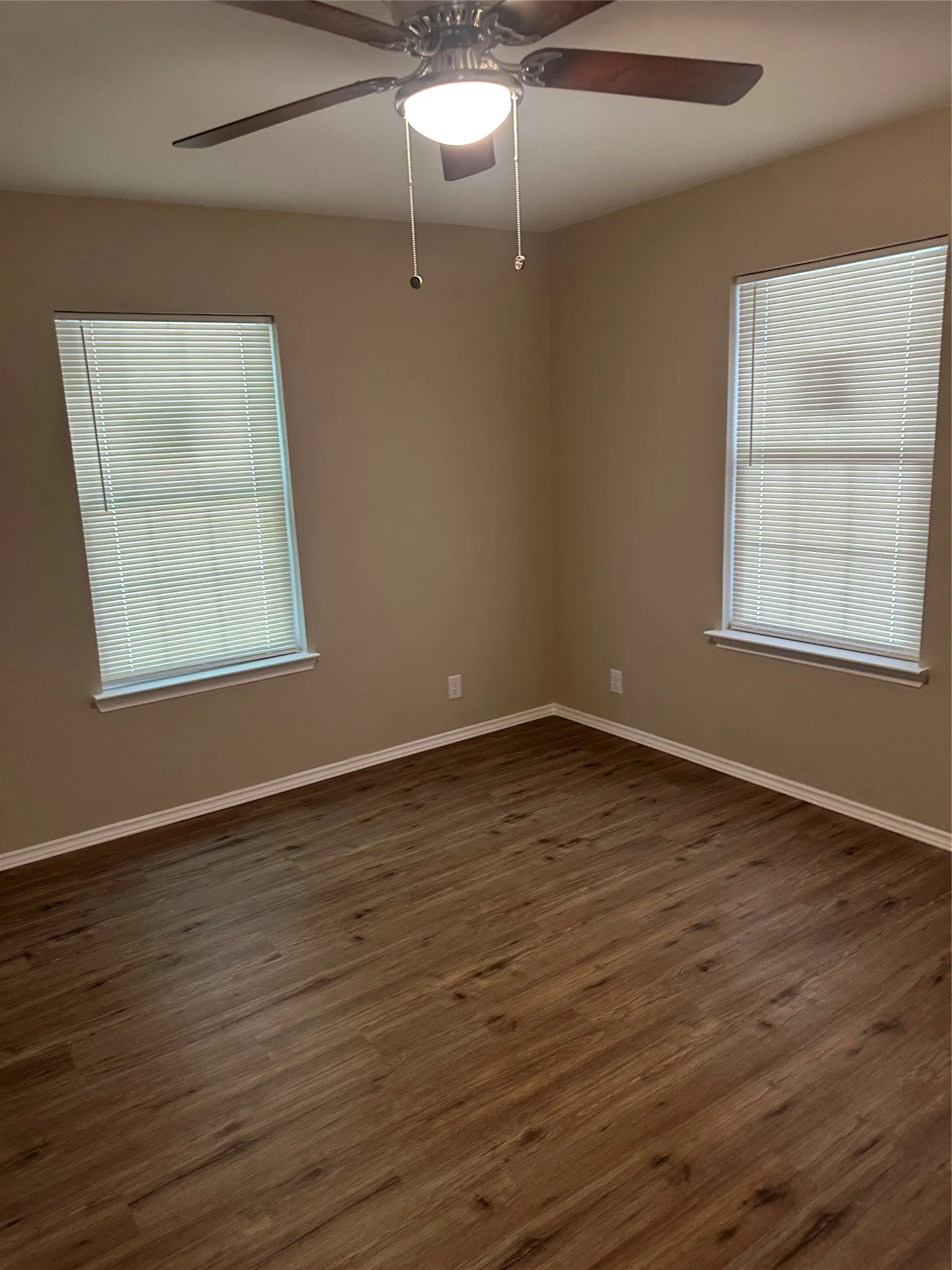 Spare room featuring dark wood-style flooring and ceiling fan