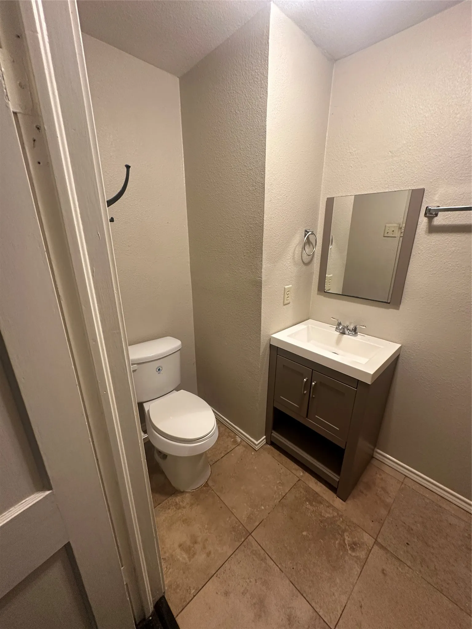 Half bath featuring a textured wall, vanity, and light tile patterned floors
