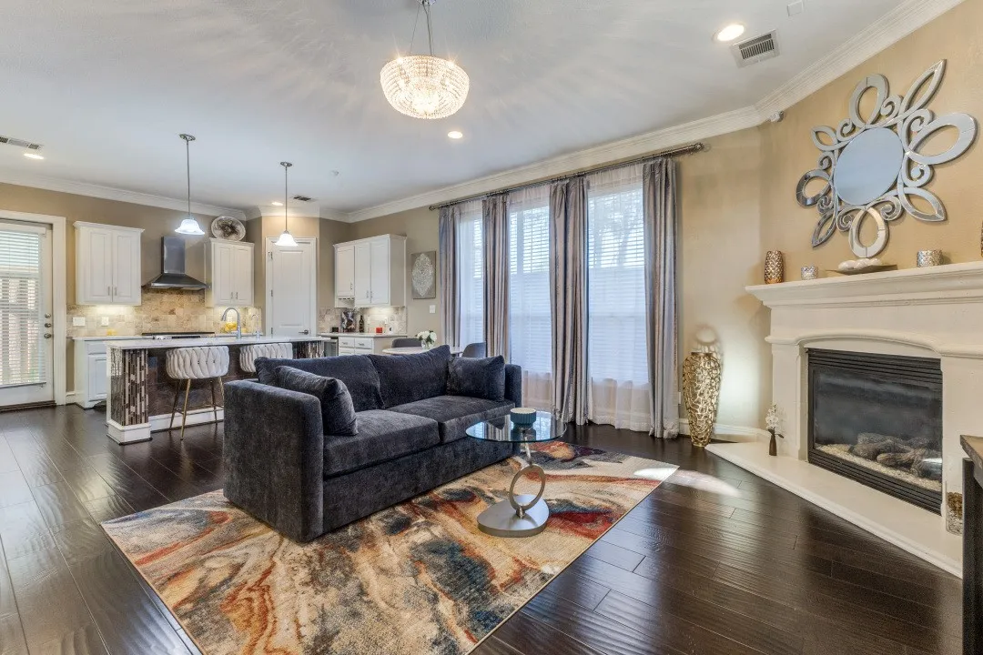 Living area featuring crown molding, dark wood finished floors, a glass covered fireplace, recessed lighting, and a chandelier