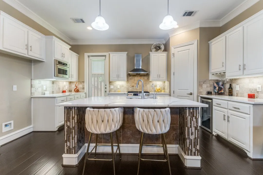 Kitchen featuring pendant lighting, white cabinets, a kitchen bar, dark wood-style flooring, and crown molding