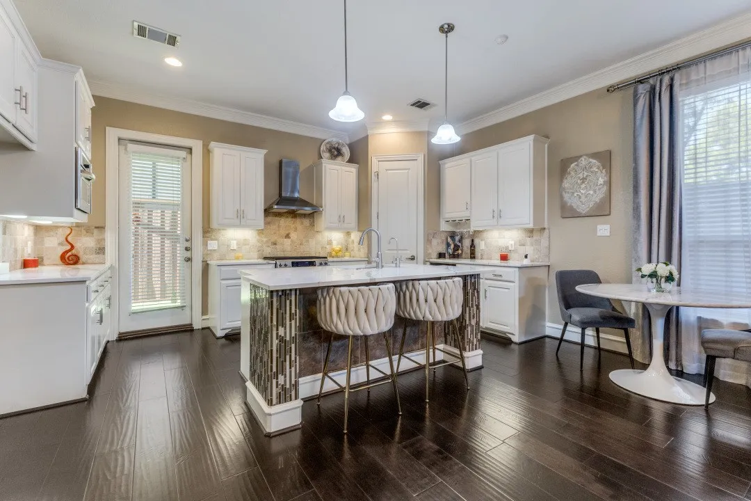 Kitchen with gas range, wall chimney exhaust hood, ornamental molding, light countertops, and white cabinetry