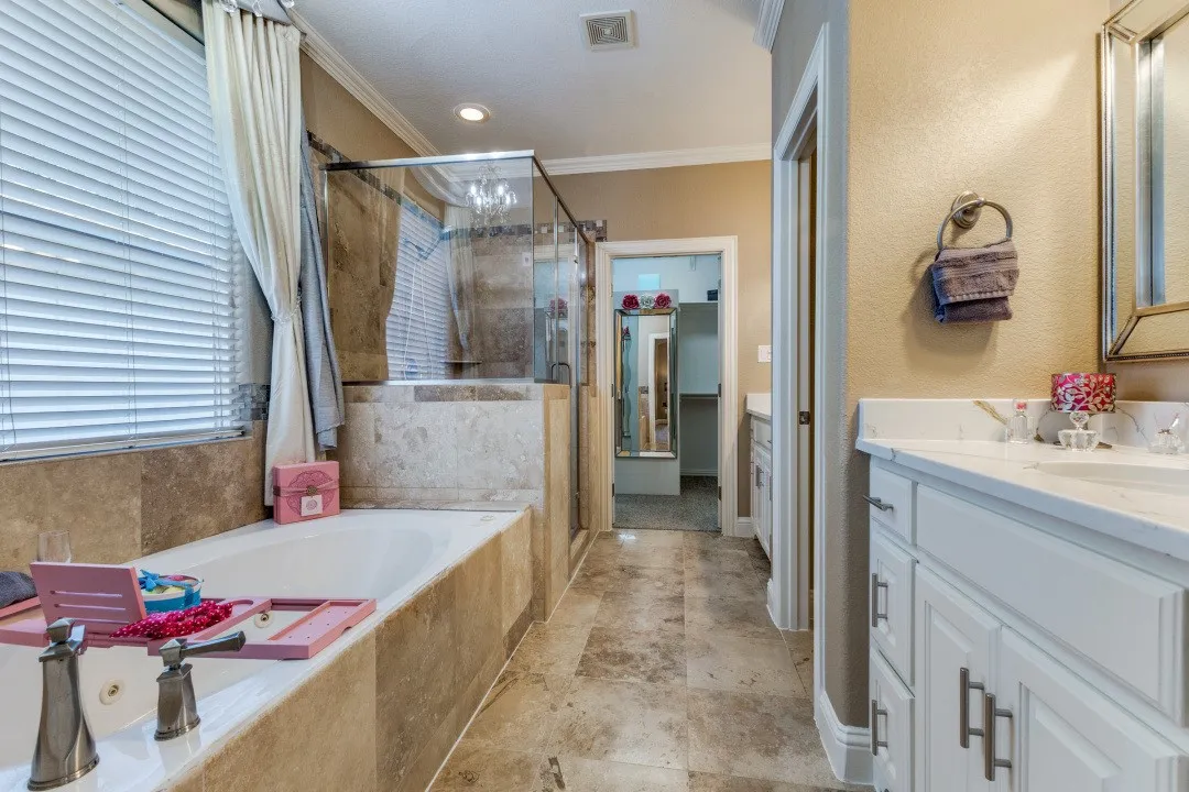 2nd floor primary
bathroom with a shower stall, a jetted tub, ornamental molding, and stone finish floors
