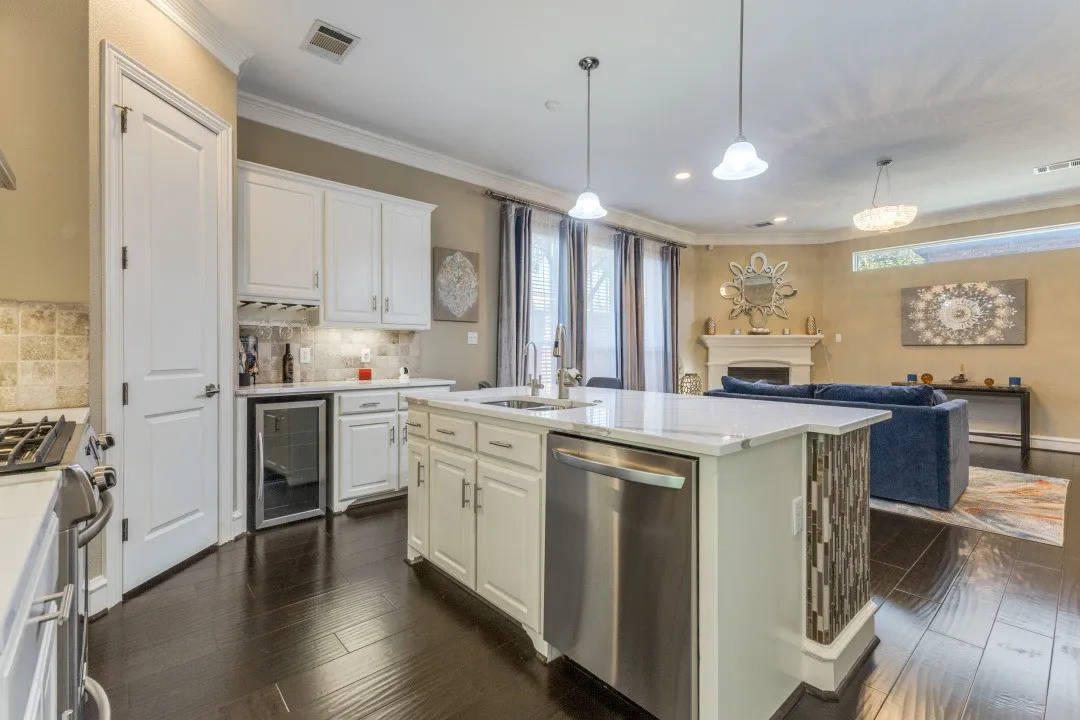 Kitchen with appliances with stainless steel finishes, beverage cooler, hanging light fixtures, open floor plan, and backsplash