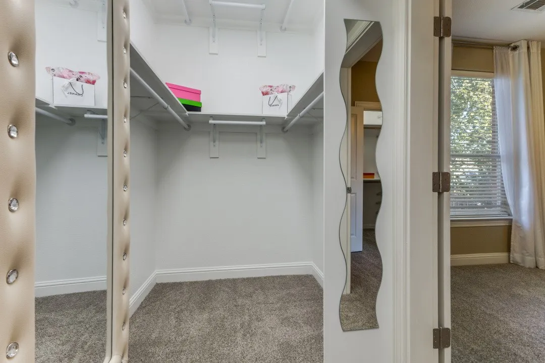 Unfurnished bedroom with attic access, light colored carpet, a spacious closet, and a ceiling fan