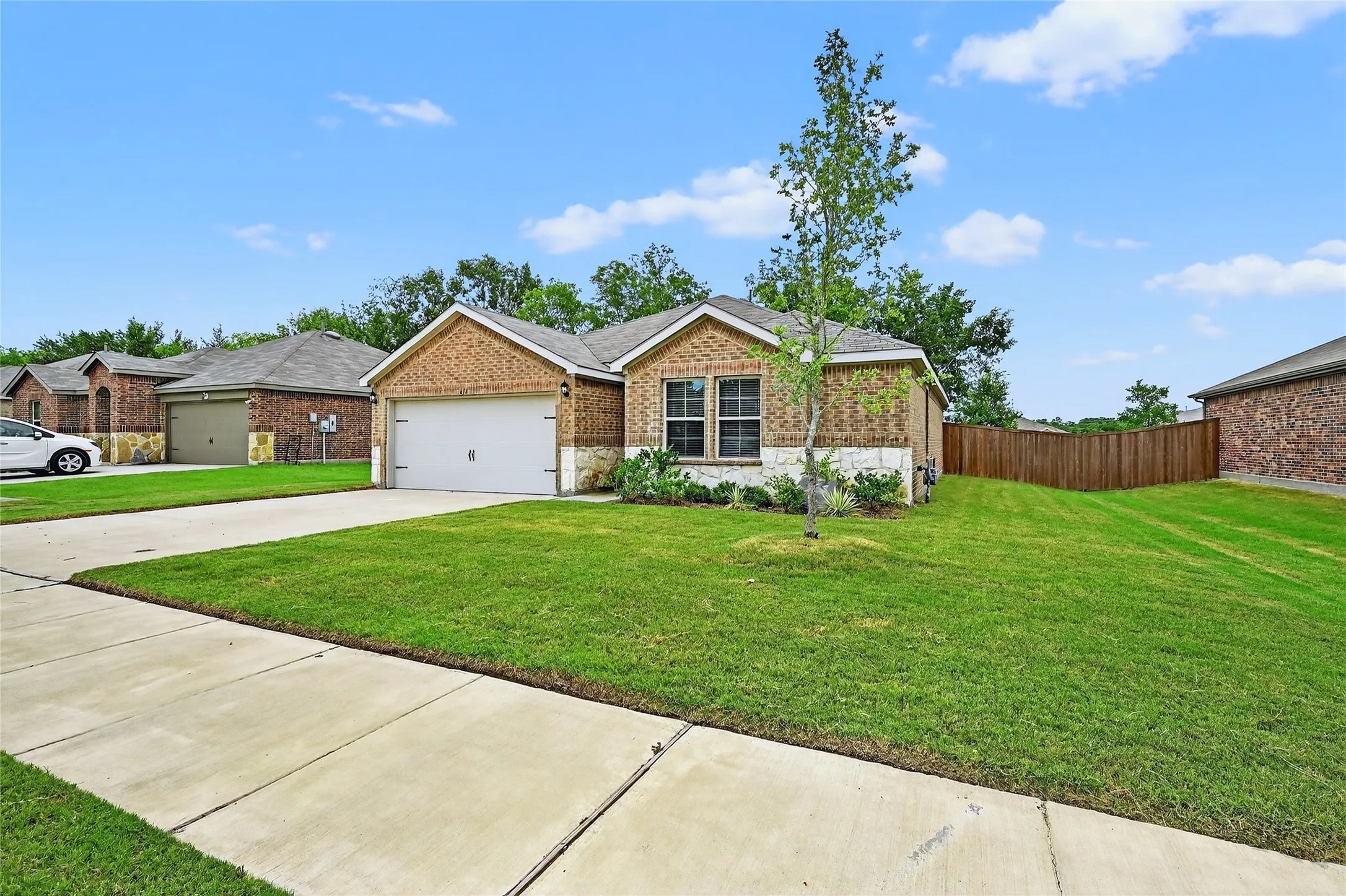 View of front of property with a garage, driveway, stone siding, and brick siding
