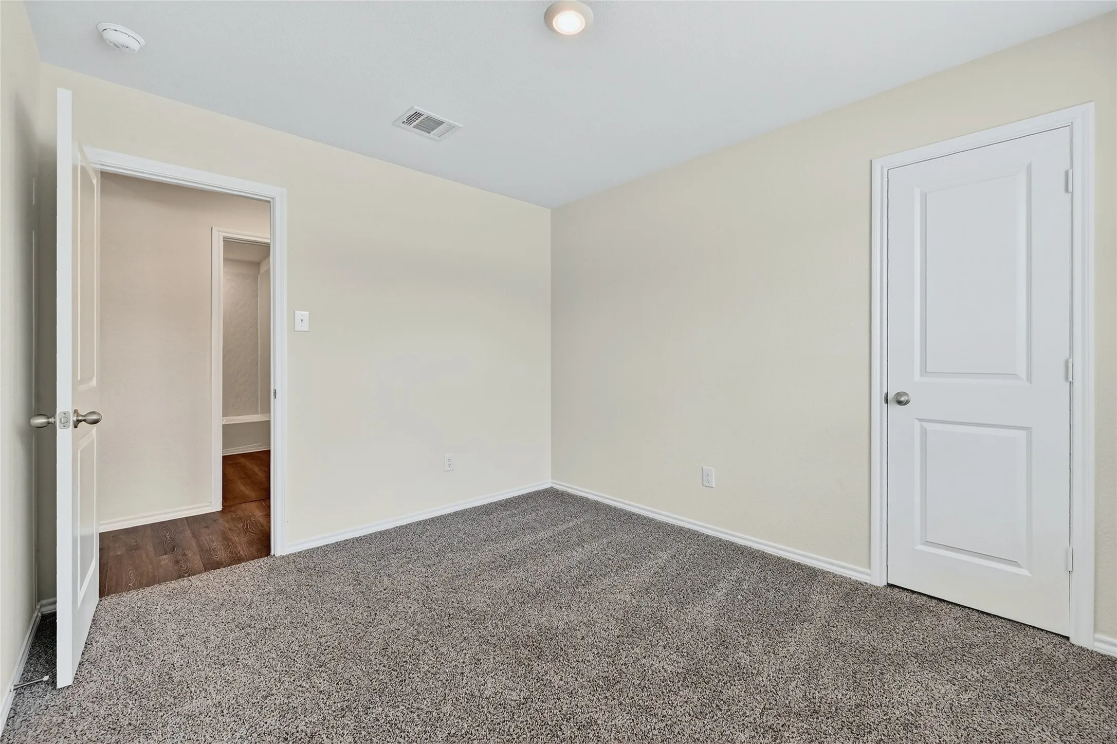 Carpeted spare room with baseboards and a smoke detector
