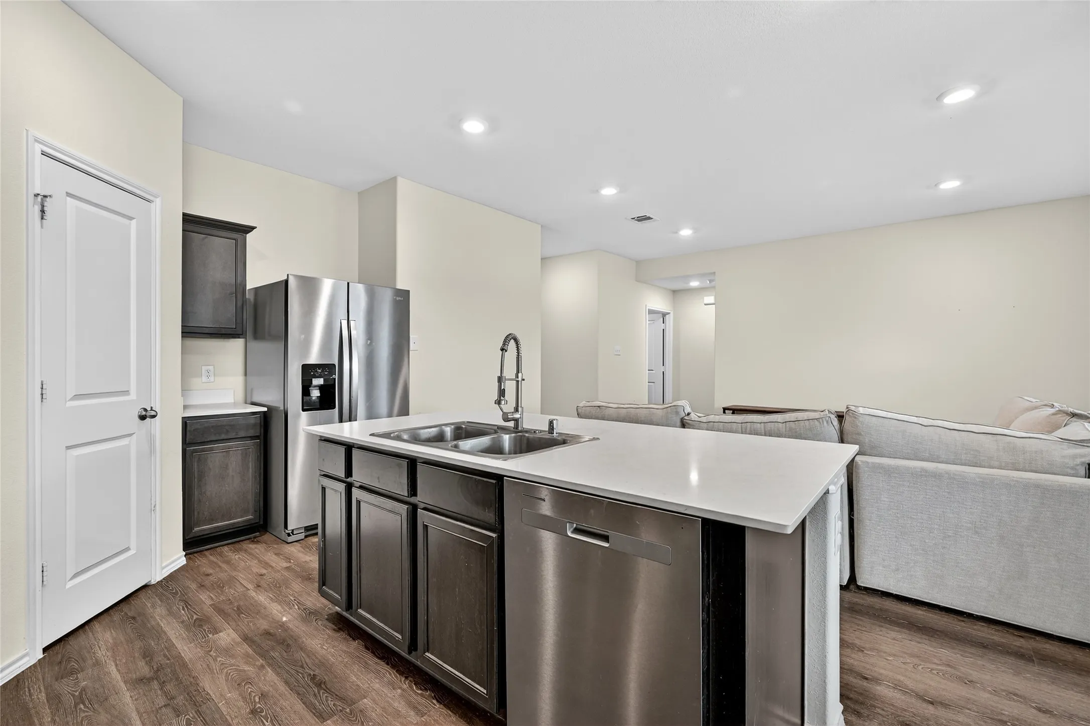 Kitchen featuring appliances with stainless steel finishes, open floor plan, dark wood-style flooring, light countertops, and recessed lighting