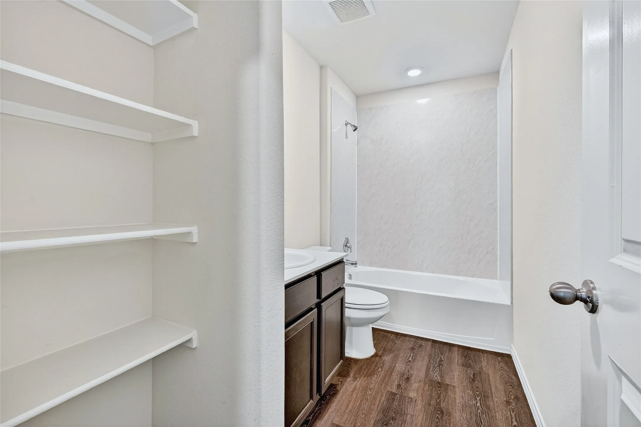 Full bath with wood finished floors, vanity, and washtub / shower combination