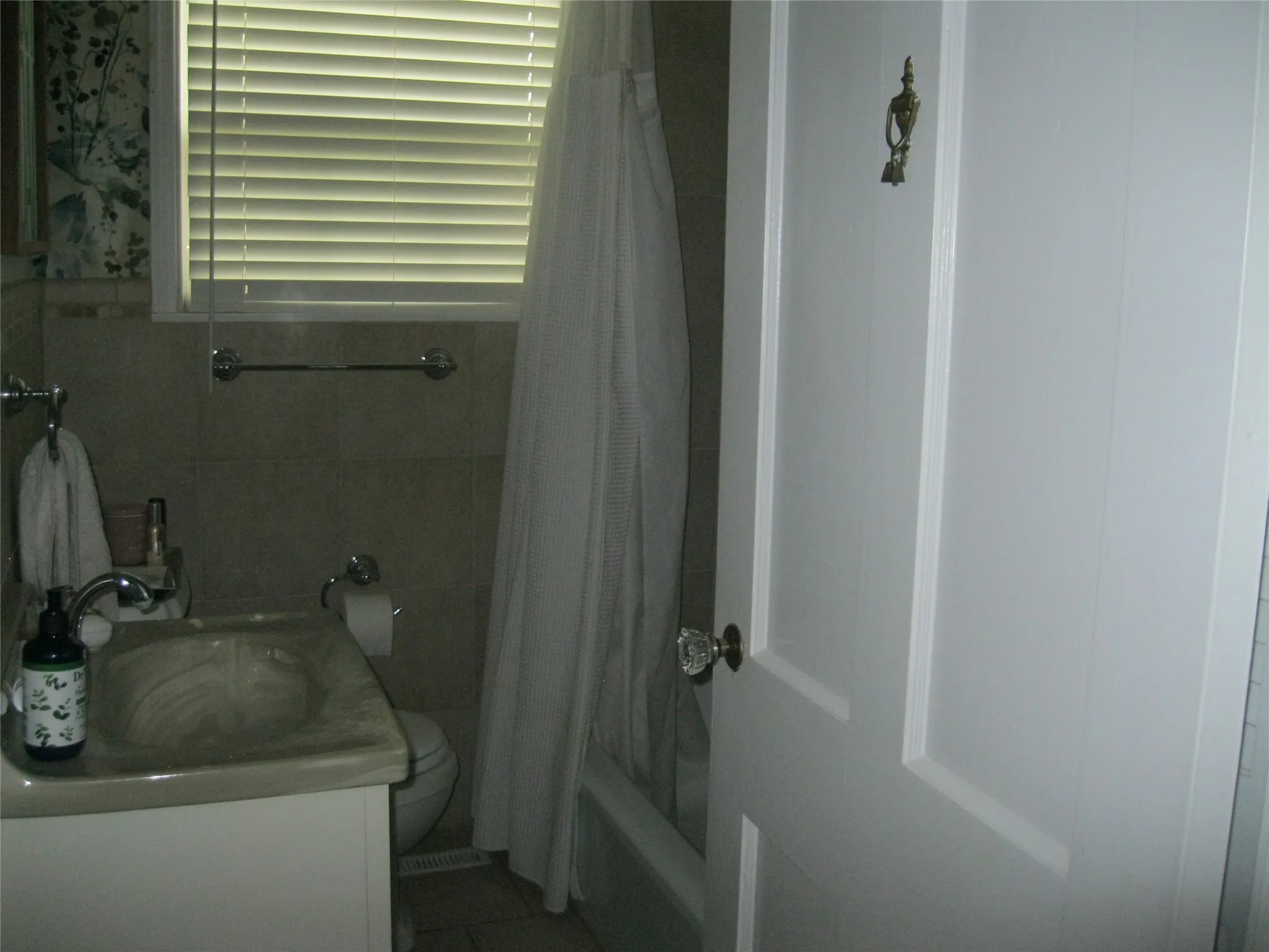 Bathroom with shower / bath combo, vanity, and tile walls