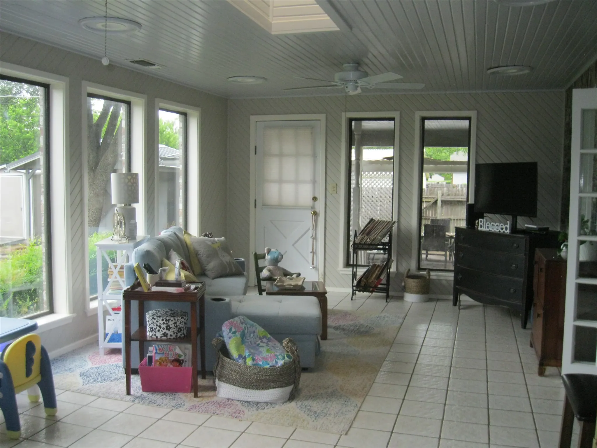 Tiled living area with plenty of natural light and a ceiling fan