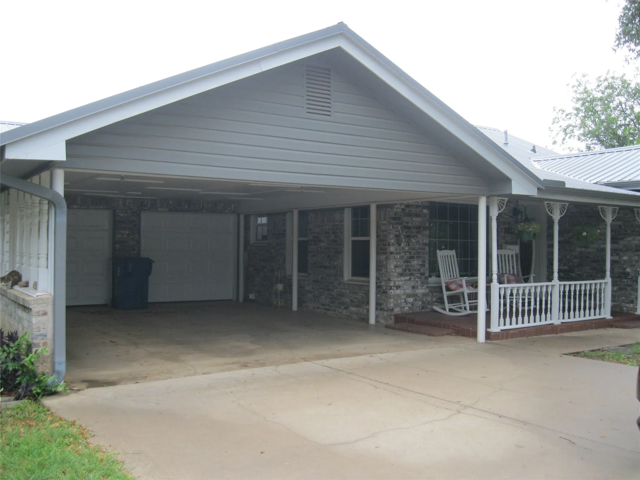 Ranch-style house featuring a porch, a garage, a metal roof, and a carport