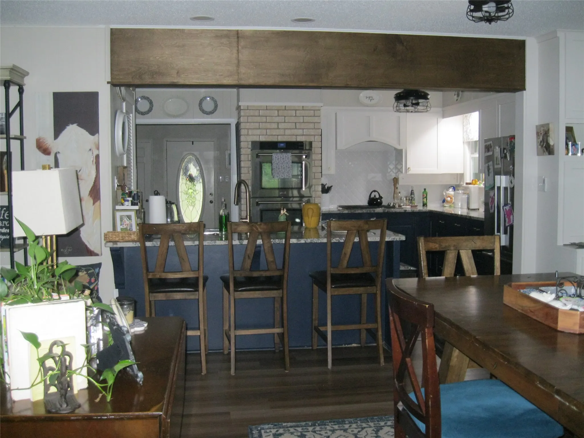 Kitchen with stainless steel double oven, dark wood-style floors, white cabinets, and freestanding refrigerator