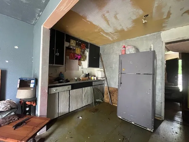 Kitchen featuring freestanding refrigerator and unfinished concrete floors
