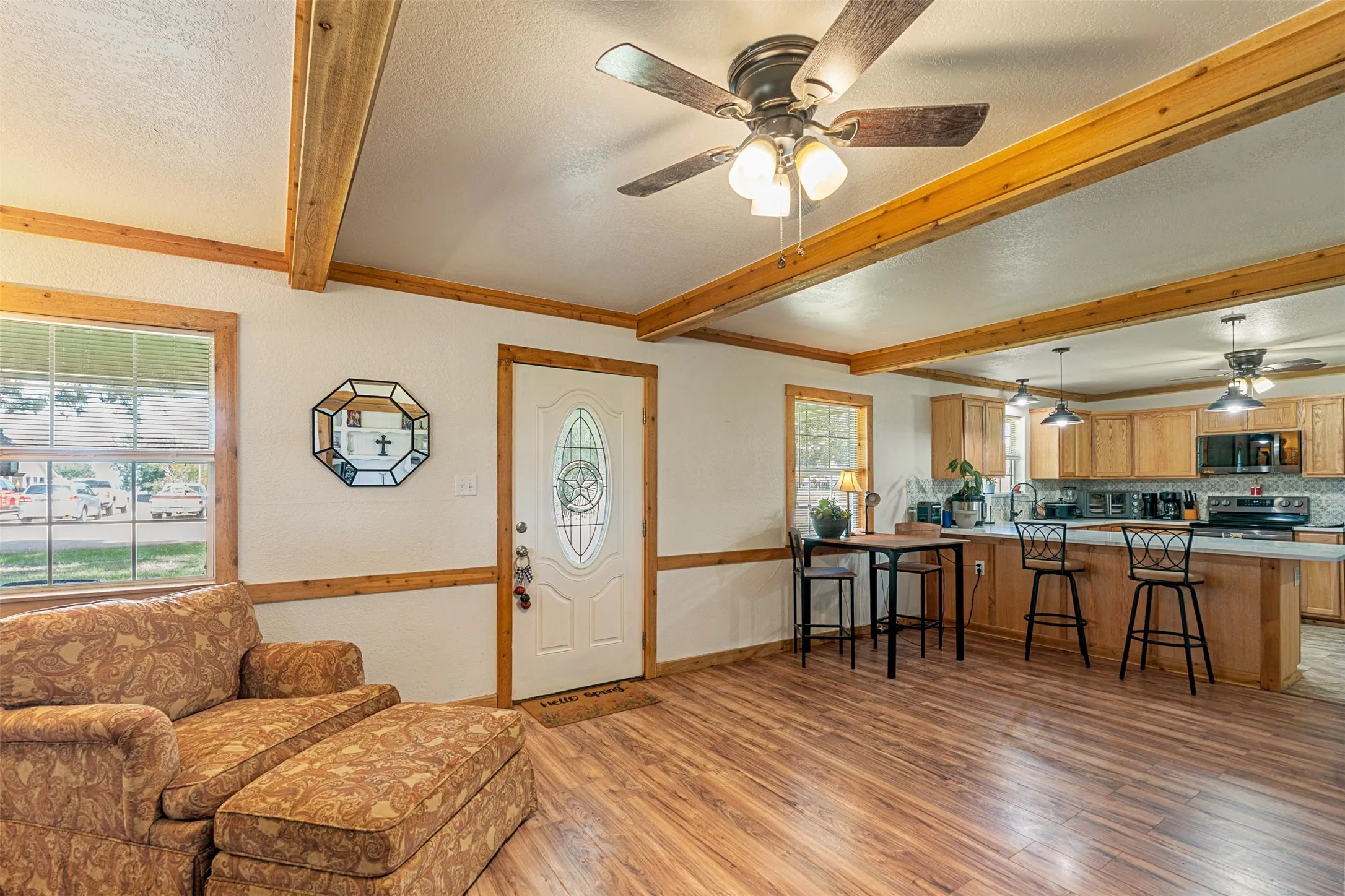 Entryway featuring ceiling fan, light wood-type flooring, beamed ceiling, healthy amount of natural light, and a textured ceiling