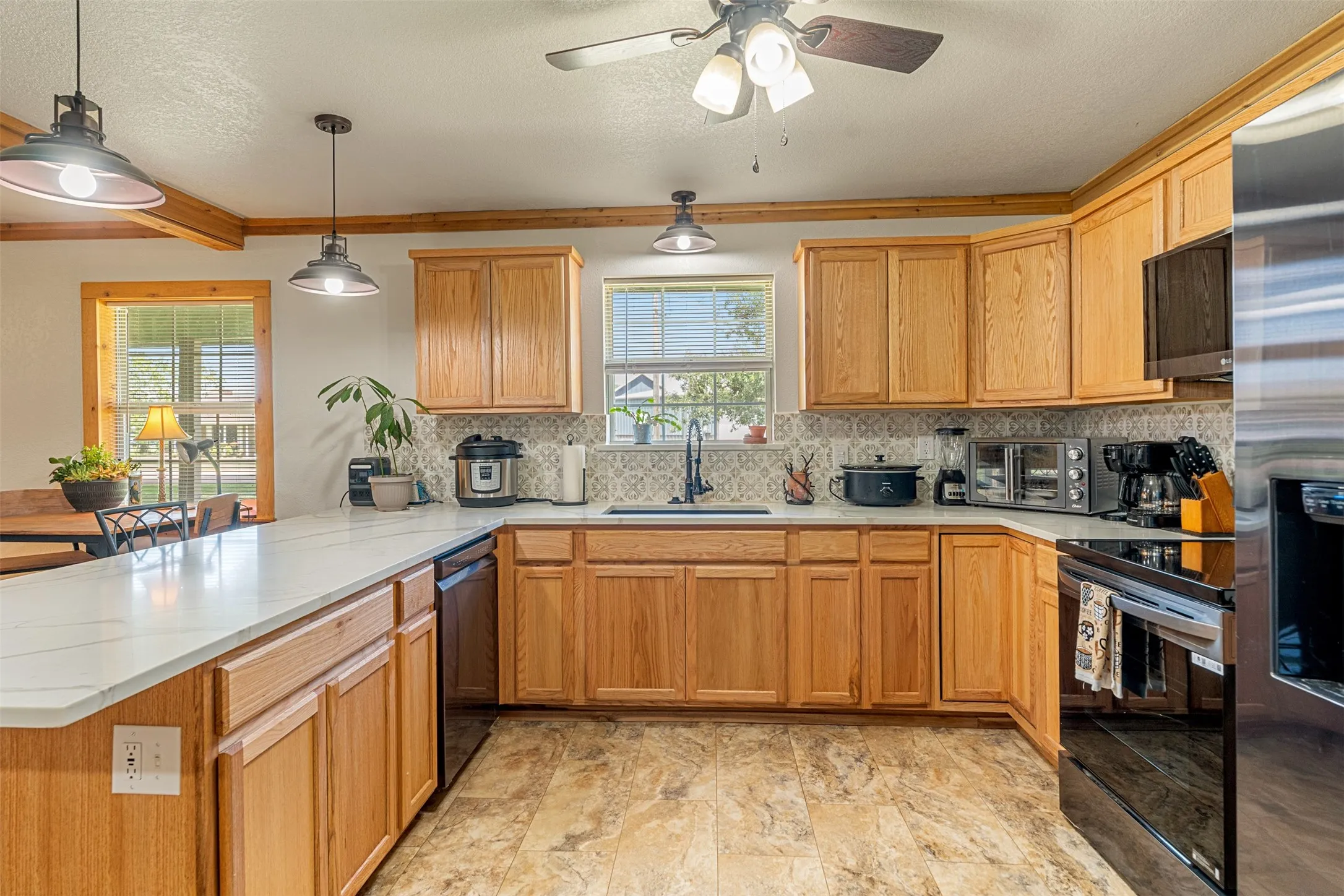 Kitchen with a peninsula, black range with electric cooktop, healthy amount of natural light, backsplash, and ornamental molding