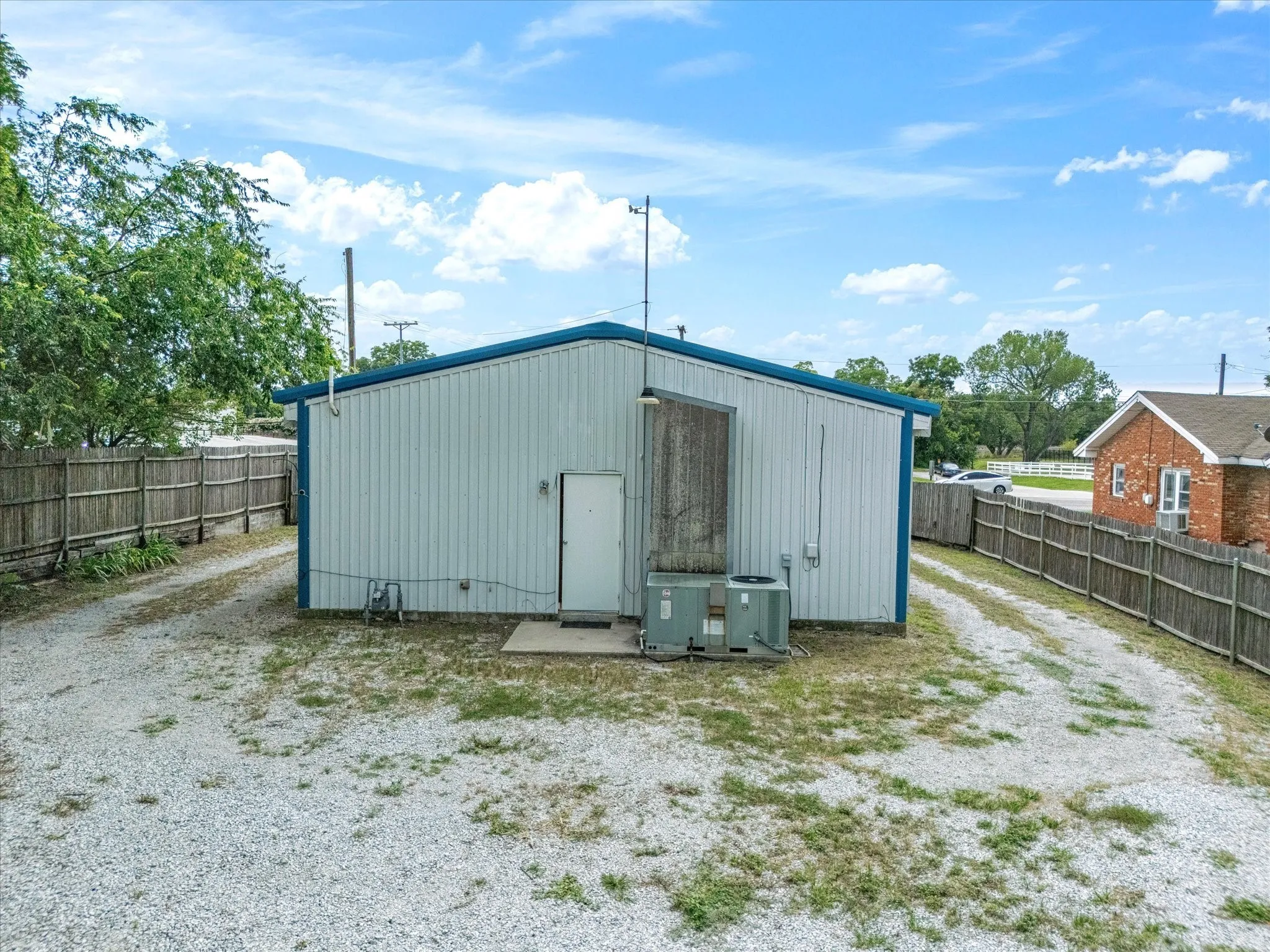 View of outdoor structure featuring a fenced parking lot and driveway