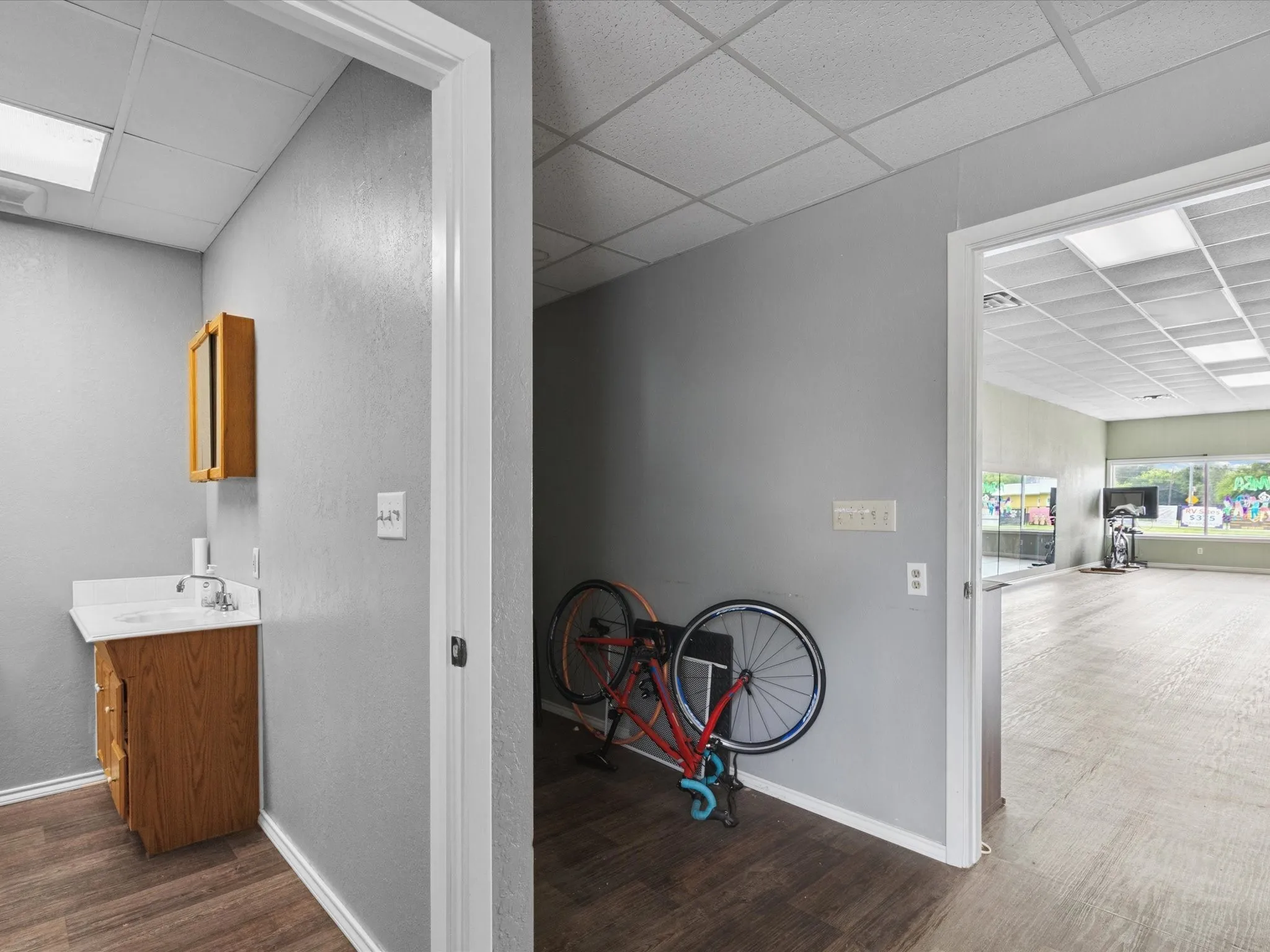 Corridor featuring a paneled ceiling and dark wood-style floors
