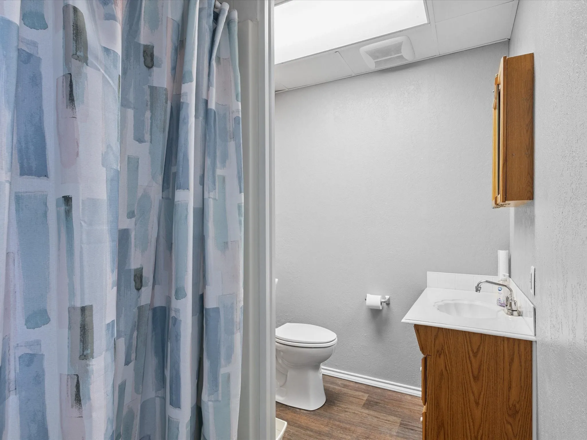 Bathroom featuring wood finished floors, vanity, a shower with shower curtain, and a drop ceiling