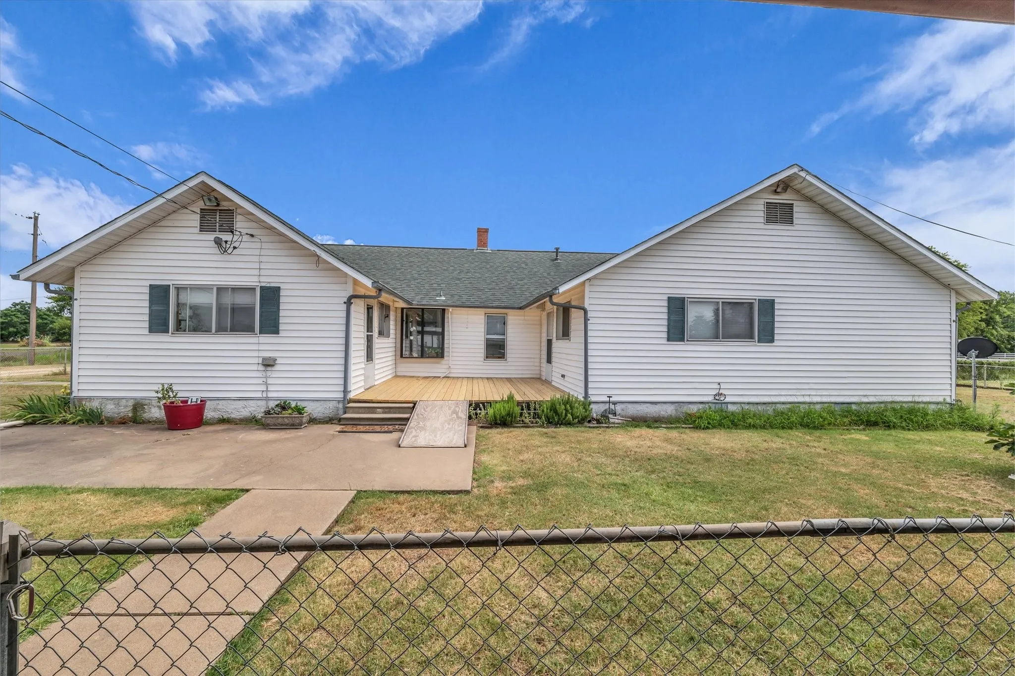 Rear view of house with a deck, roof with shingles, and a patio area
