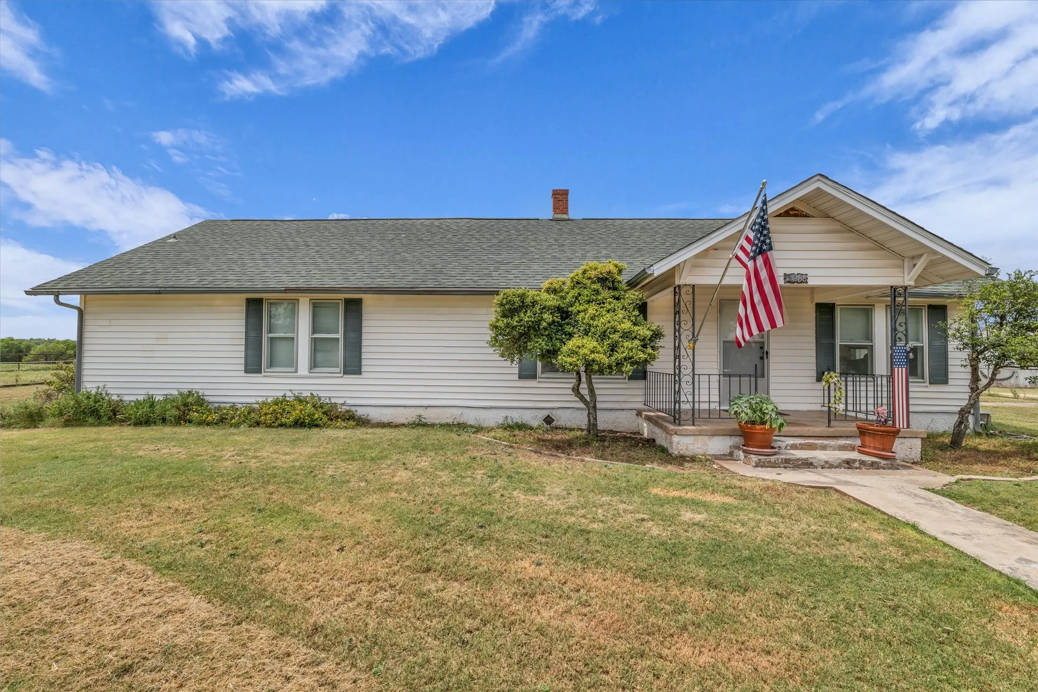 View of front of property with a porch, a front lawn, and roof with shingles