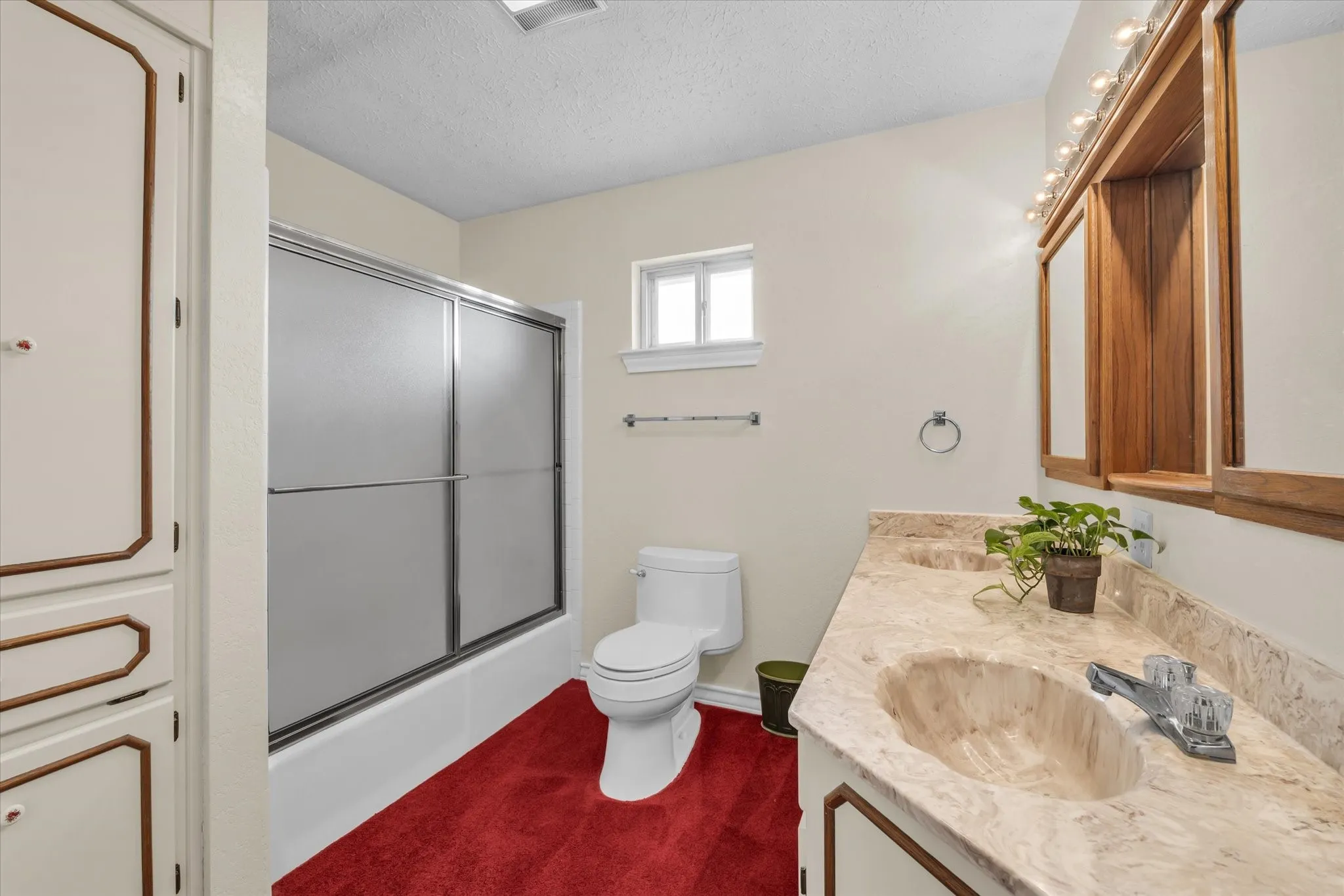 Bathroom with vanity, shower / bath combination with glass door, and a textured ceiling