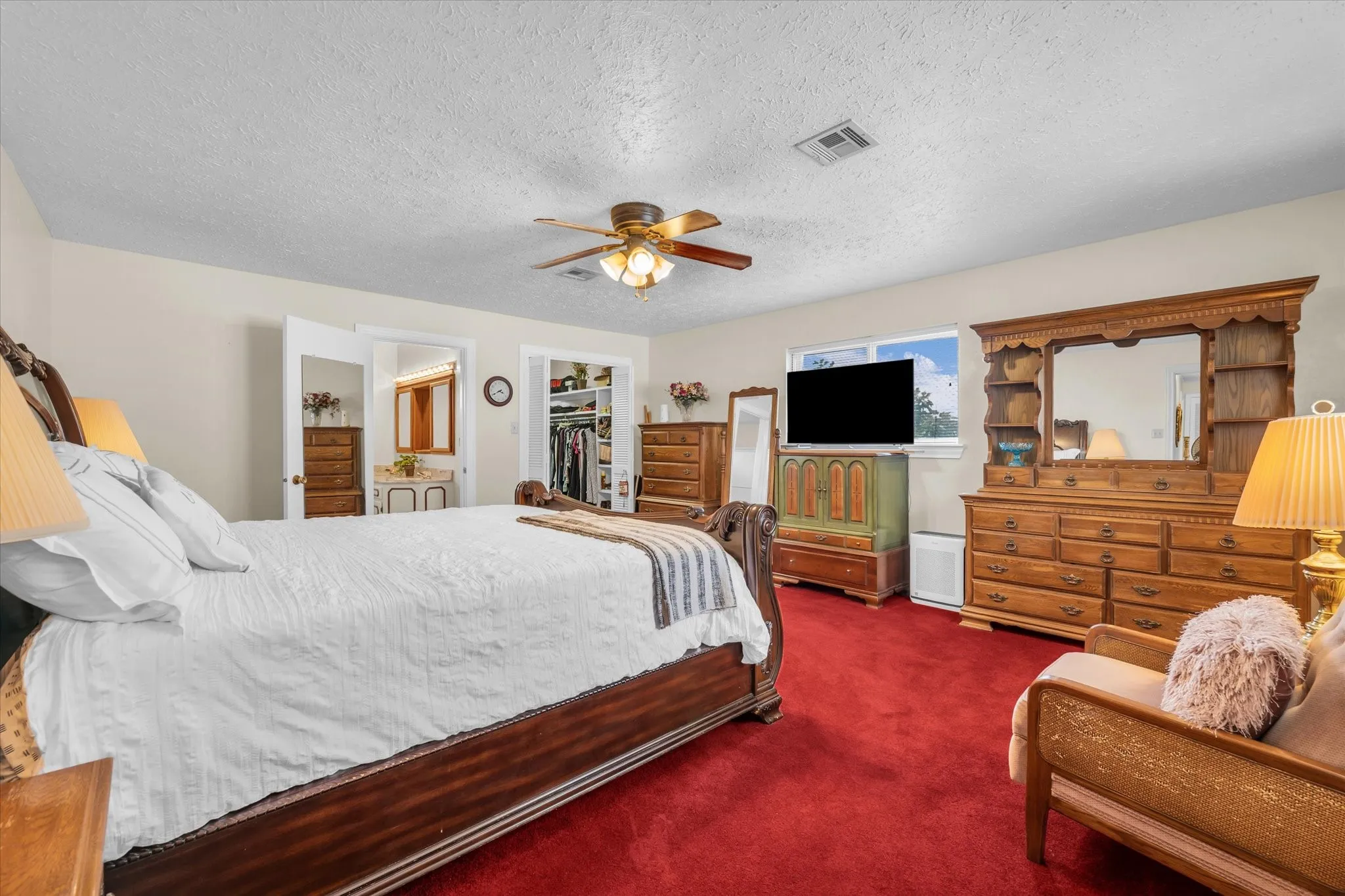 Bedroom with carpet flooring, a spacious closet, a textured ceiling, a closet, and a ceiling fan