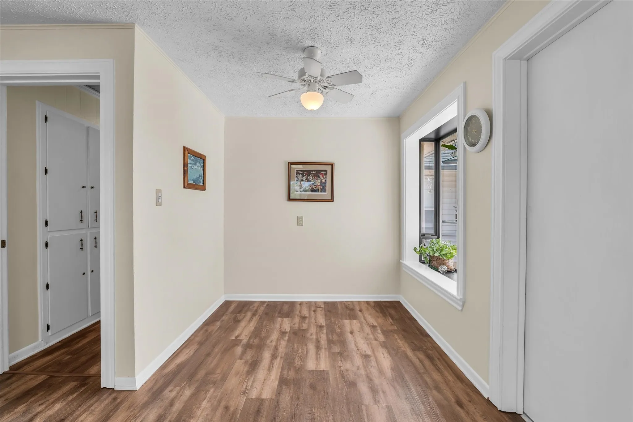 Spare room with wood finished floors, a ceiling fan, and a textured ceiling