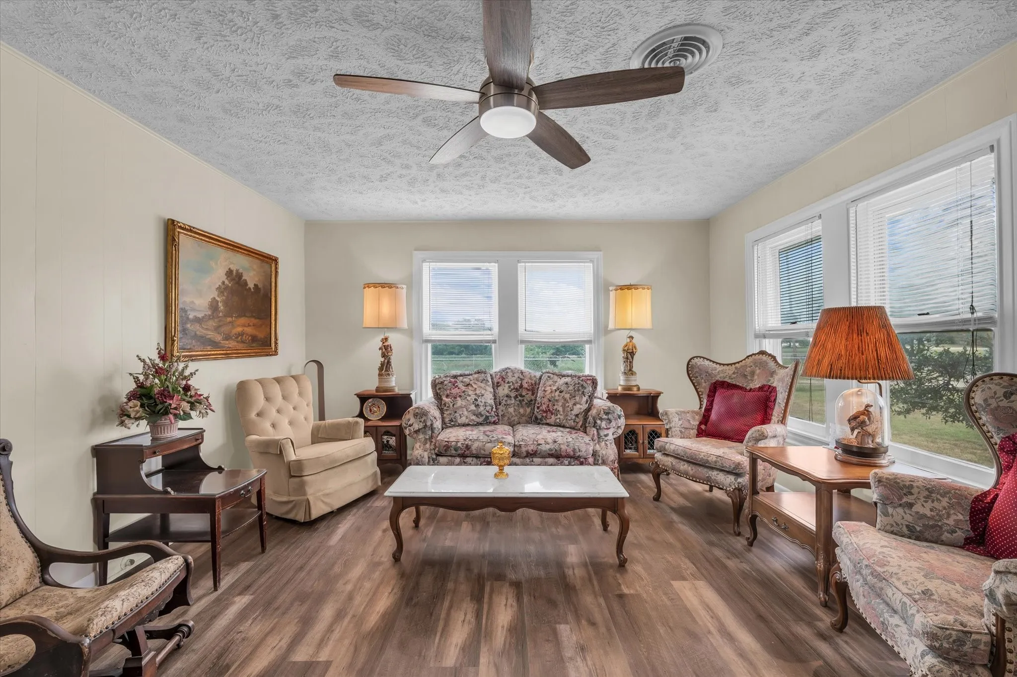 Living room with a textured ceiling, wood finished floors, and ceiling fan
