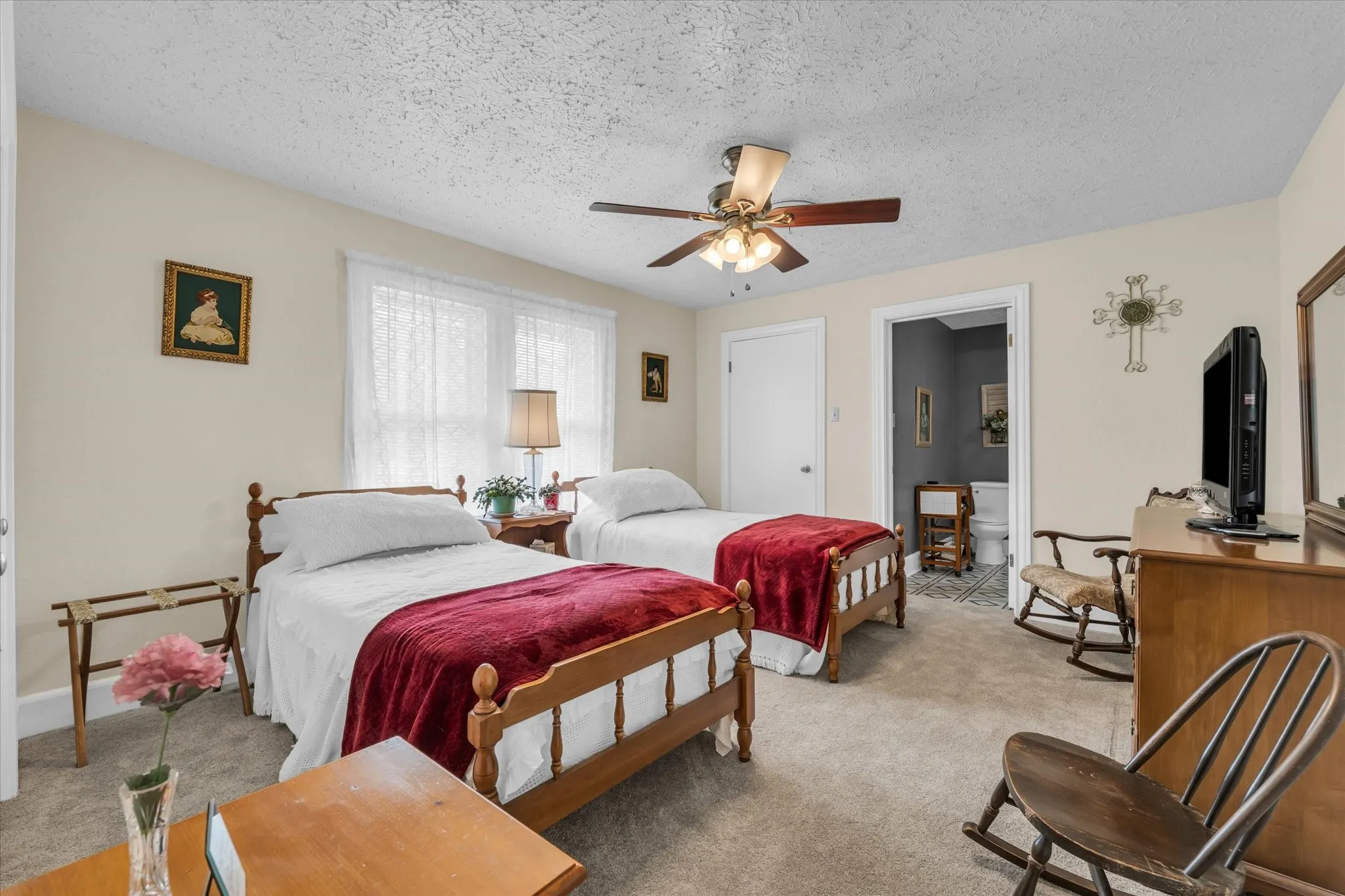 Bedroom with light carpet, a textured ceiling, ceiling fan, and ensuite bath