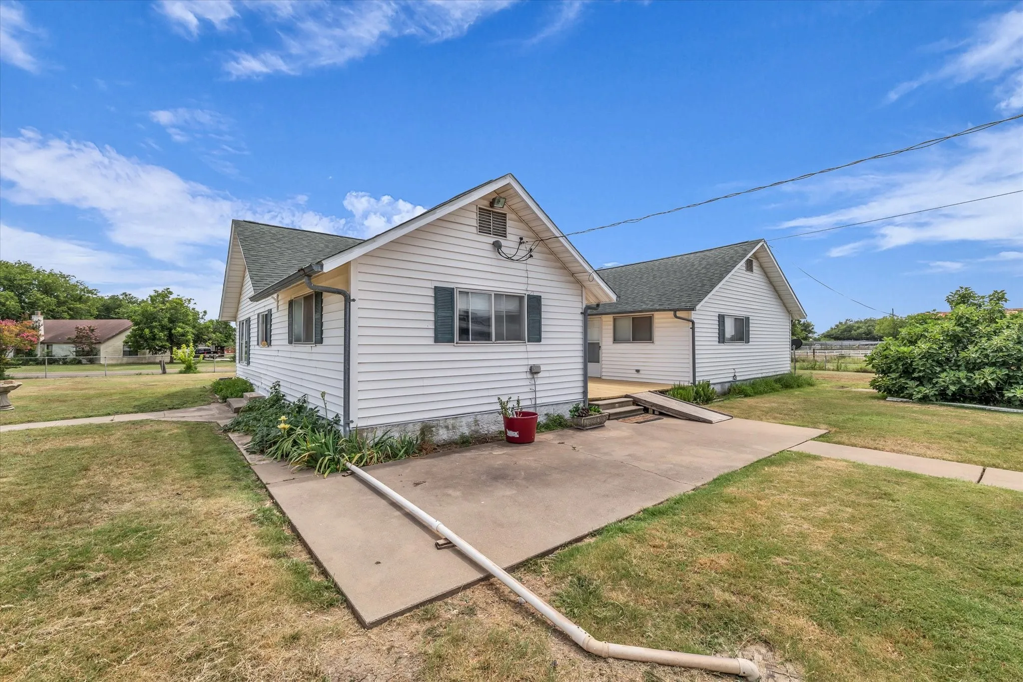 View of front of home with roof with shingles, a patio, and a front lawn