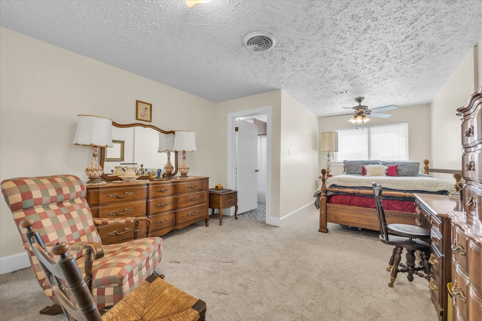 Bedroom with light carpet, ceiling fan, and a textured ceiling