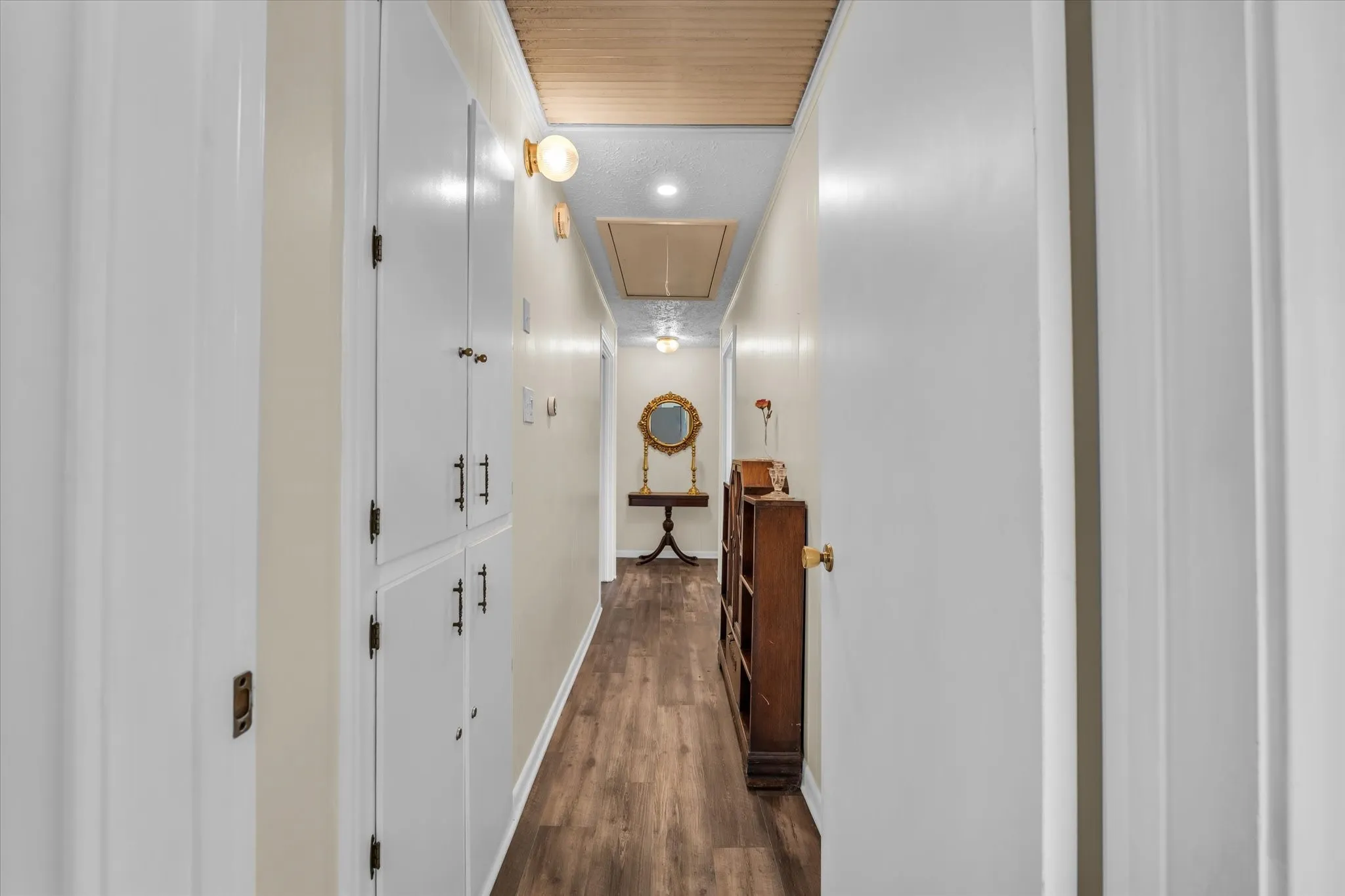 Hall featuring attic access and dark wood-style flooring
